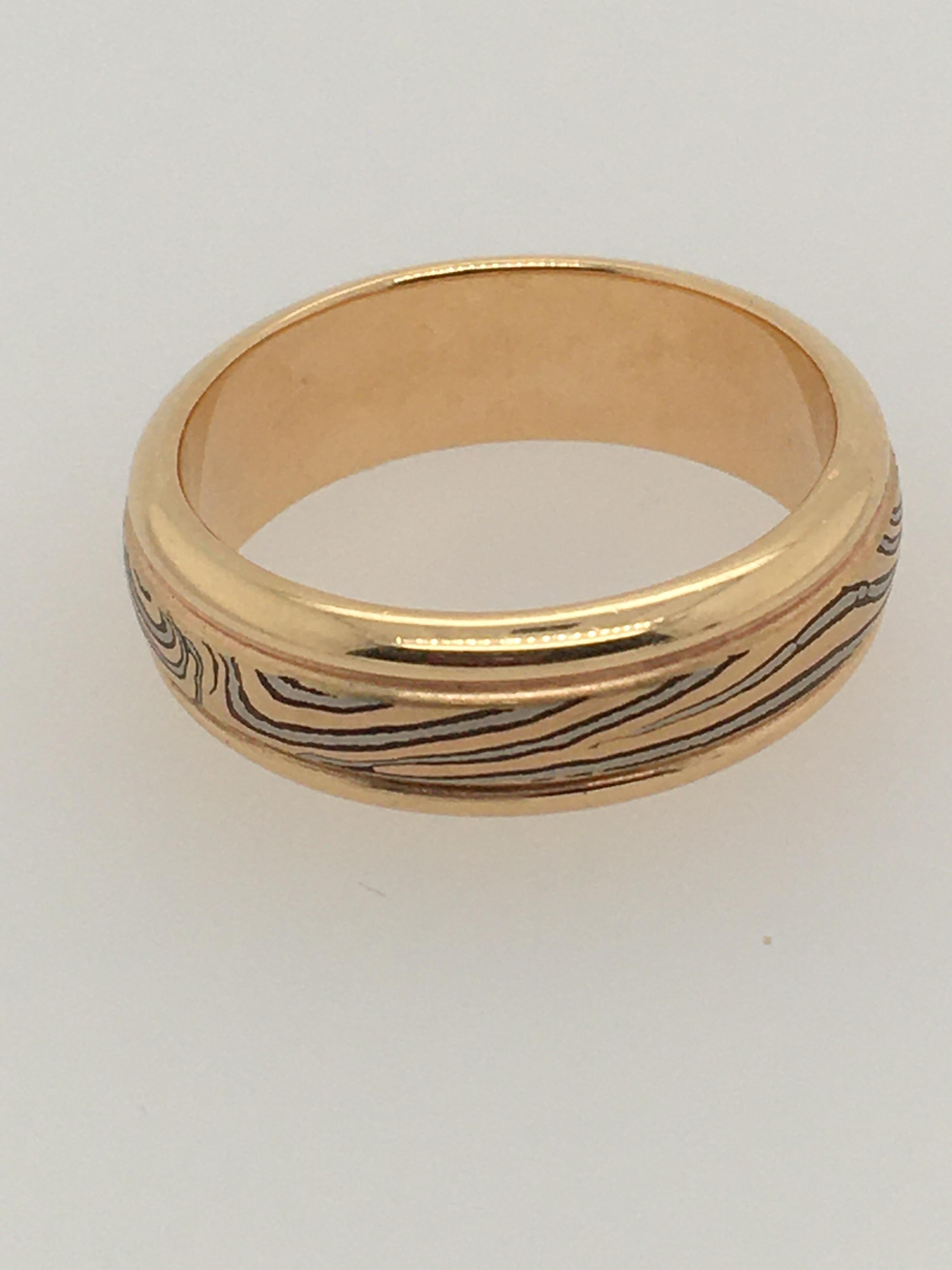 A striking handcrafted 7 mm Mokume round edge band by George Sawyer.  The band features a distinctive design of 14K gold edges surrounding rose and gray gold.  Style Number is RE7YB.  Interior stamp reads 