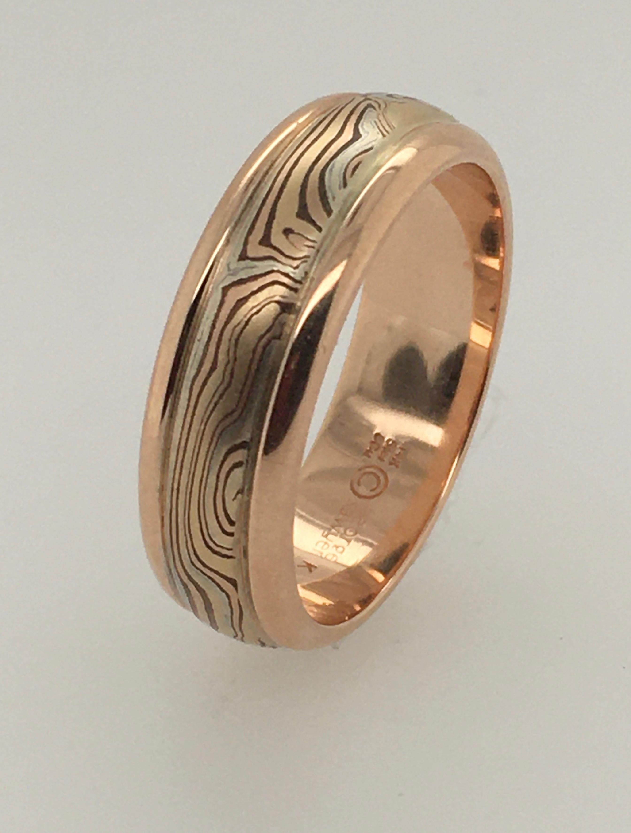 This beautiful hand-wrought George Sawyer 7 mm Mokume round-edged band features 14K red and yellow gold edges surrounding the distinctive sterling silver & etched copper.  The interior is stamped 