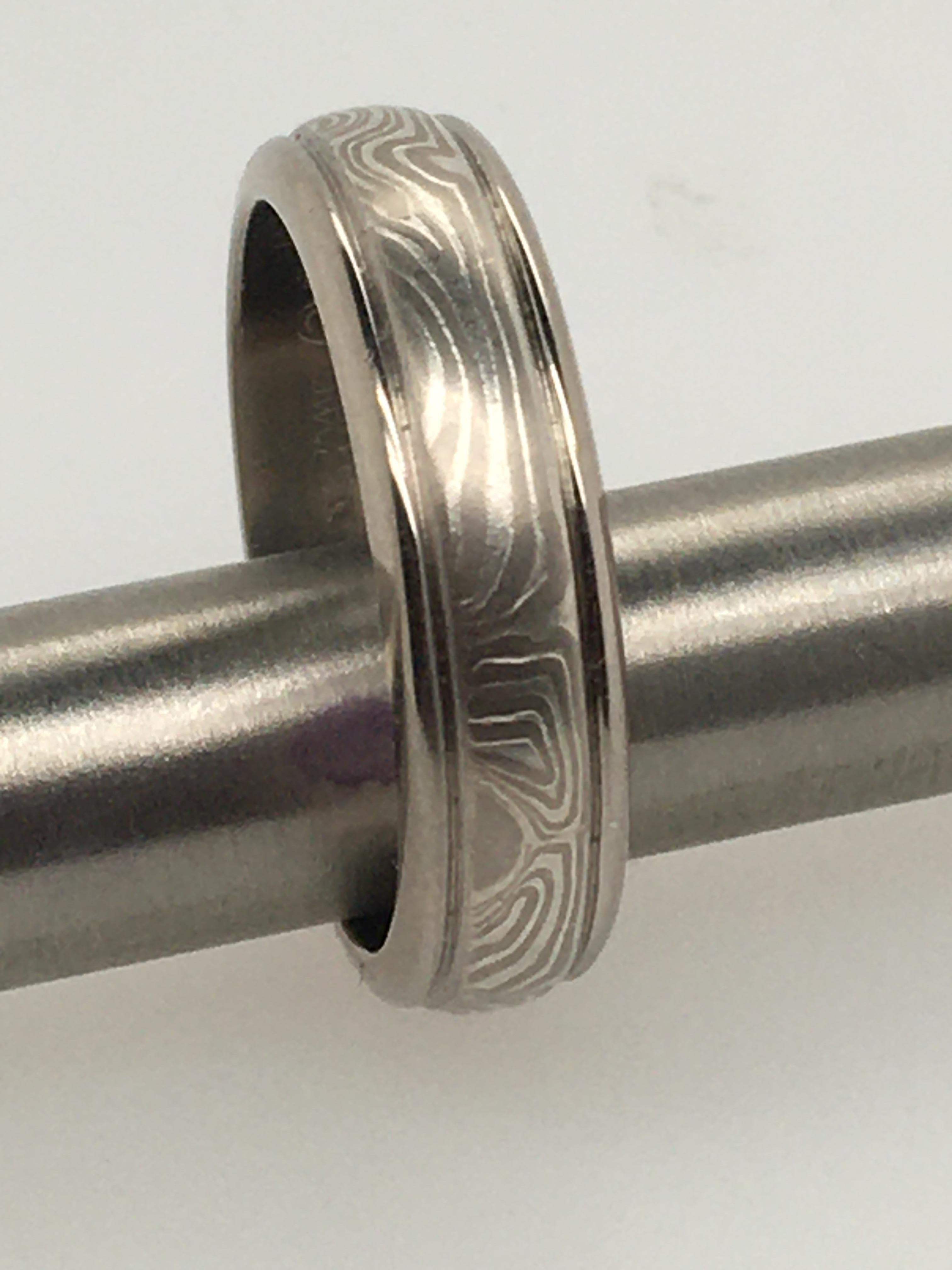 This handsome handcrafted George Sawyer 6 mm Mokume round-edged band features 14K gray gold & etched sterling silver, surrounded by a 14K gray gold edge. The interior is stamped 