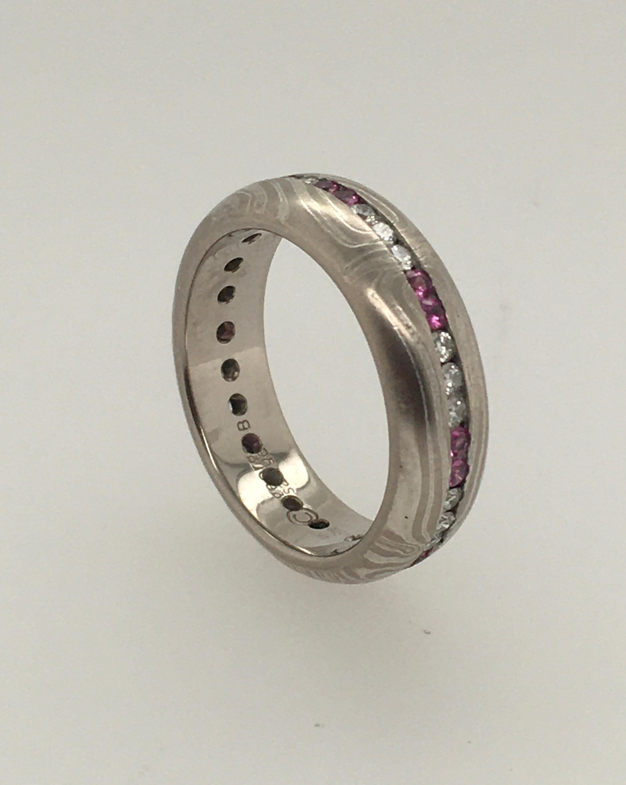 A striking George Sawyer symmetry* wedding band in the traditional Mokume style. This band features 1.5 mm pink sapphires .35 ct & .36 ct diamonds, in a repeating pattern of 3 diamonds/2 sapphires, with 14 K White Gold and Sterling Silver. The Style