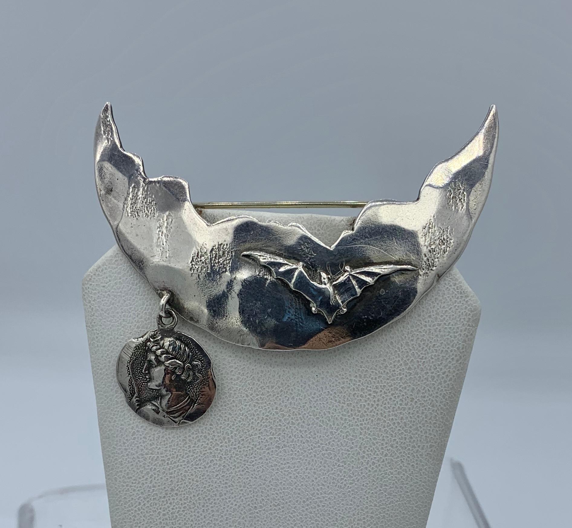 This is an extraordinary Brooch by George W. Shiebler and Company in the form of a moon with a bat flying across the moon with one of Shiebler's iconic Homeric pendants hanging from the moon.  The absolutely wonderful design in Sterling Silver with