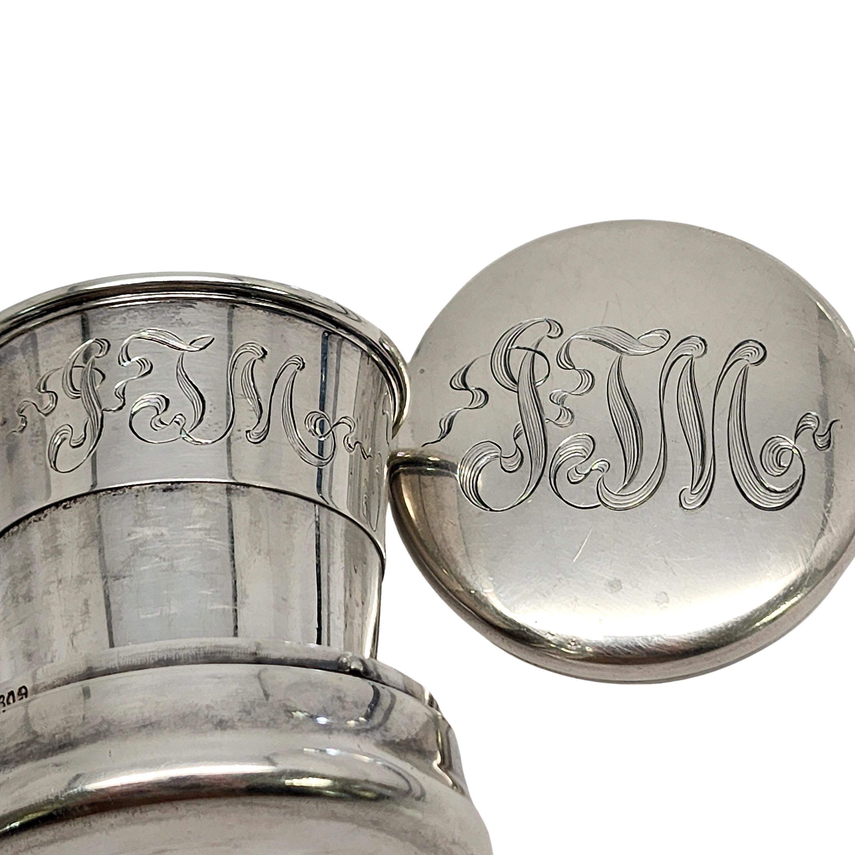 Sterling silver collapsible travel cup with gold wash interior by George W Shiebler with monograms.

Monogram appears to be JTM (on the lid and on the cup)

This travel cup features a telescoping design that collapses into itself with a monogrammed