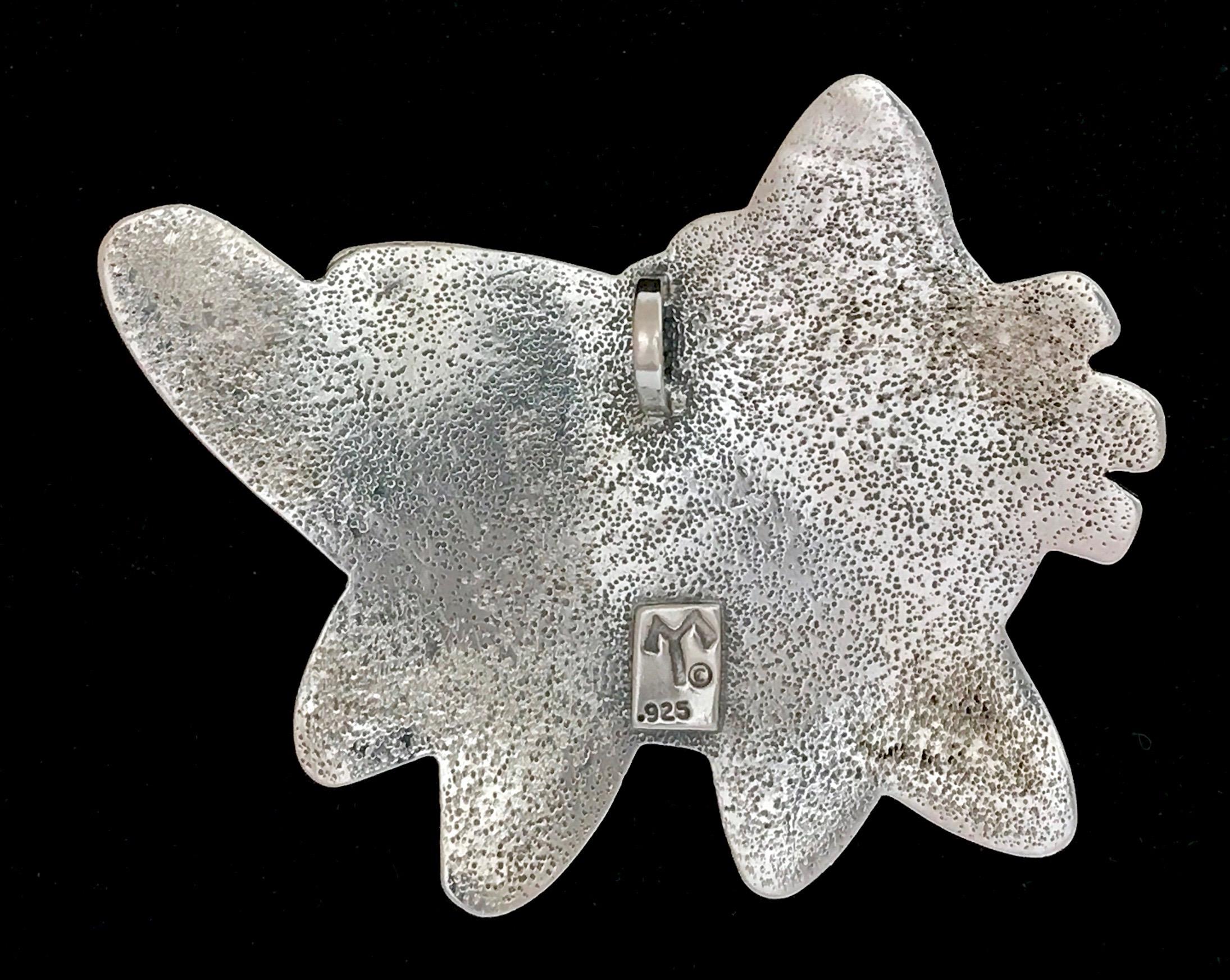George Silversmith is From Wide Ruins, gattino, ciondolo, Melanie Yazzie, Navajo 

Melanie A. Yazzie (Navajo-Diné) è un'artista multimediale molto apprezzata, conosciuta per le sue stampe, i suoi dipinti, le sue sculture e i suoi design di