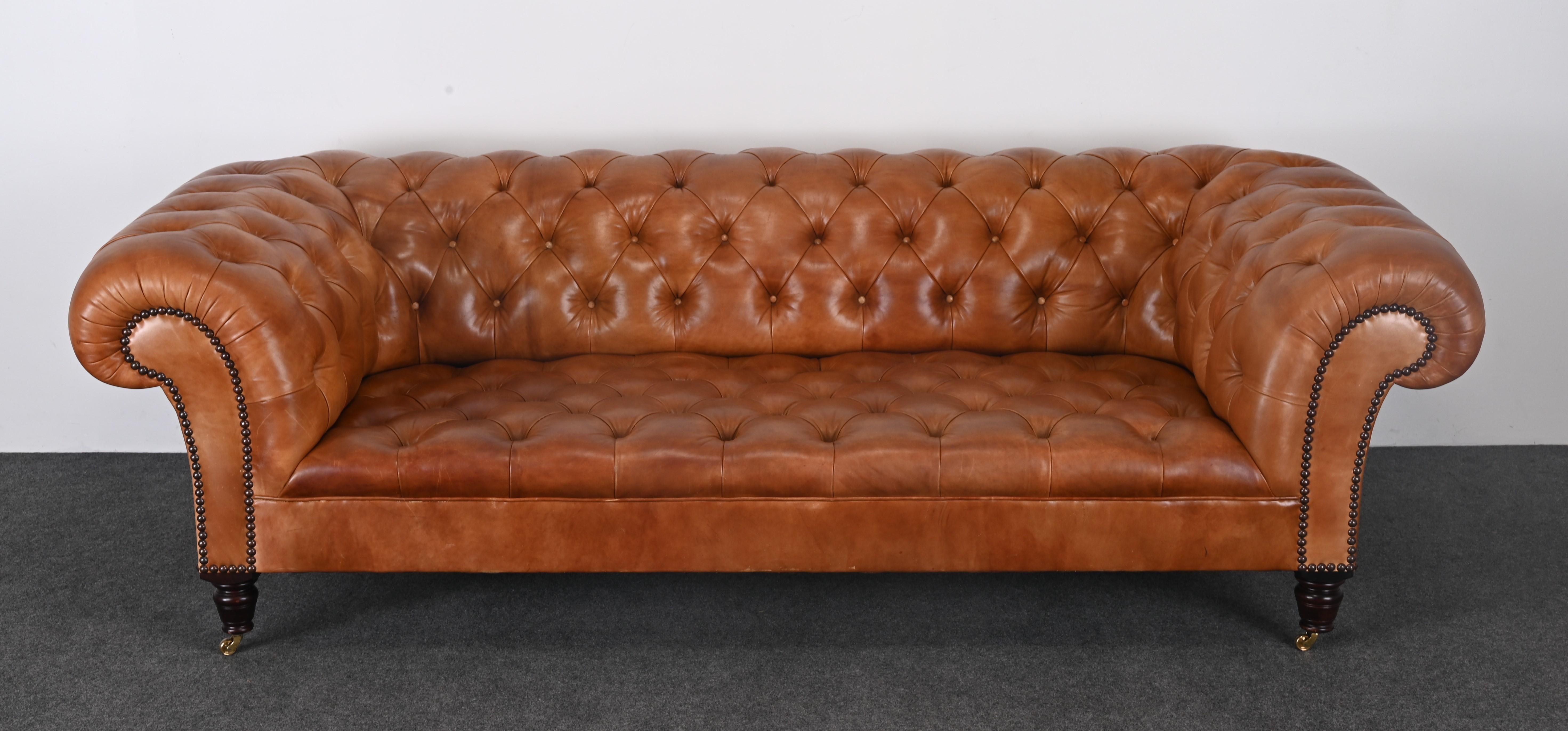 A handsome George Smith classic Chesterfield leather sofa in whiskey tone. This sofa has antique distressed leather and is made of kiln-dried hardwood with heavy steel coiled springs and horsehair. The legacy of George Smith furniture is its