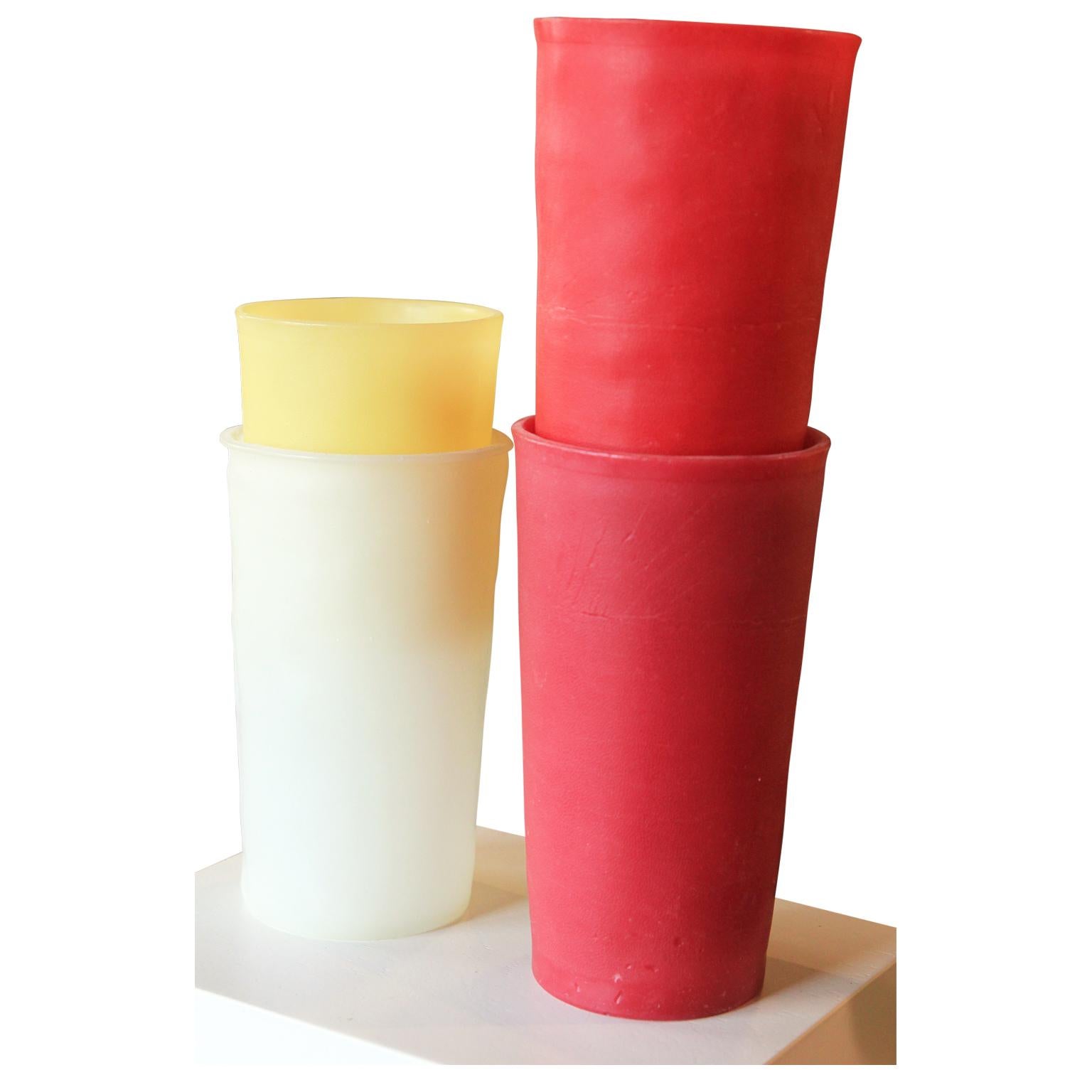 Modern collection of realistically rendered tupperware cups made out of beeswax and pigment by California artist George Stoll. The piece features a set of four red, yellow, and white cups neatly stacked on a white square base that can be hung on a