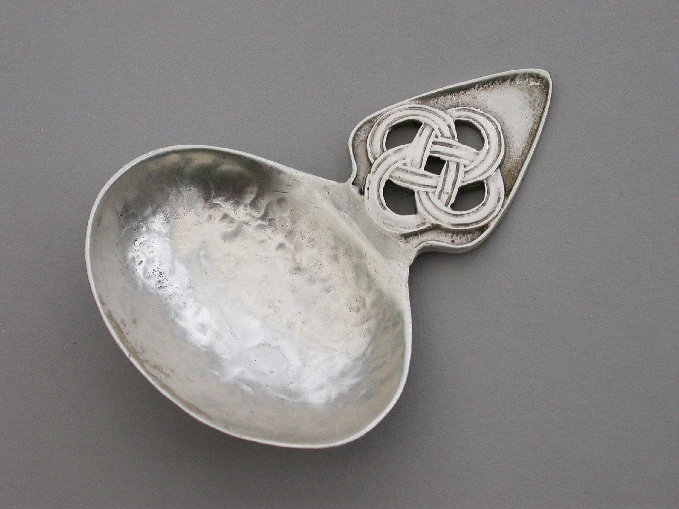 A good quality early 20th century cast silver caddy spoon made in the Arts and Crafts style with hammered sideways oval bowl and pierced Celtic knot type handle.

By Sandheim Brothers, London, 1920

Weight 19.00 Grams (0.61 troy ounces).