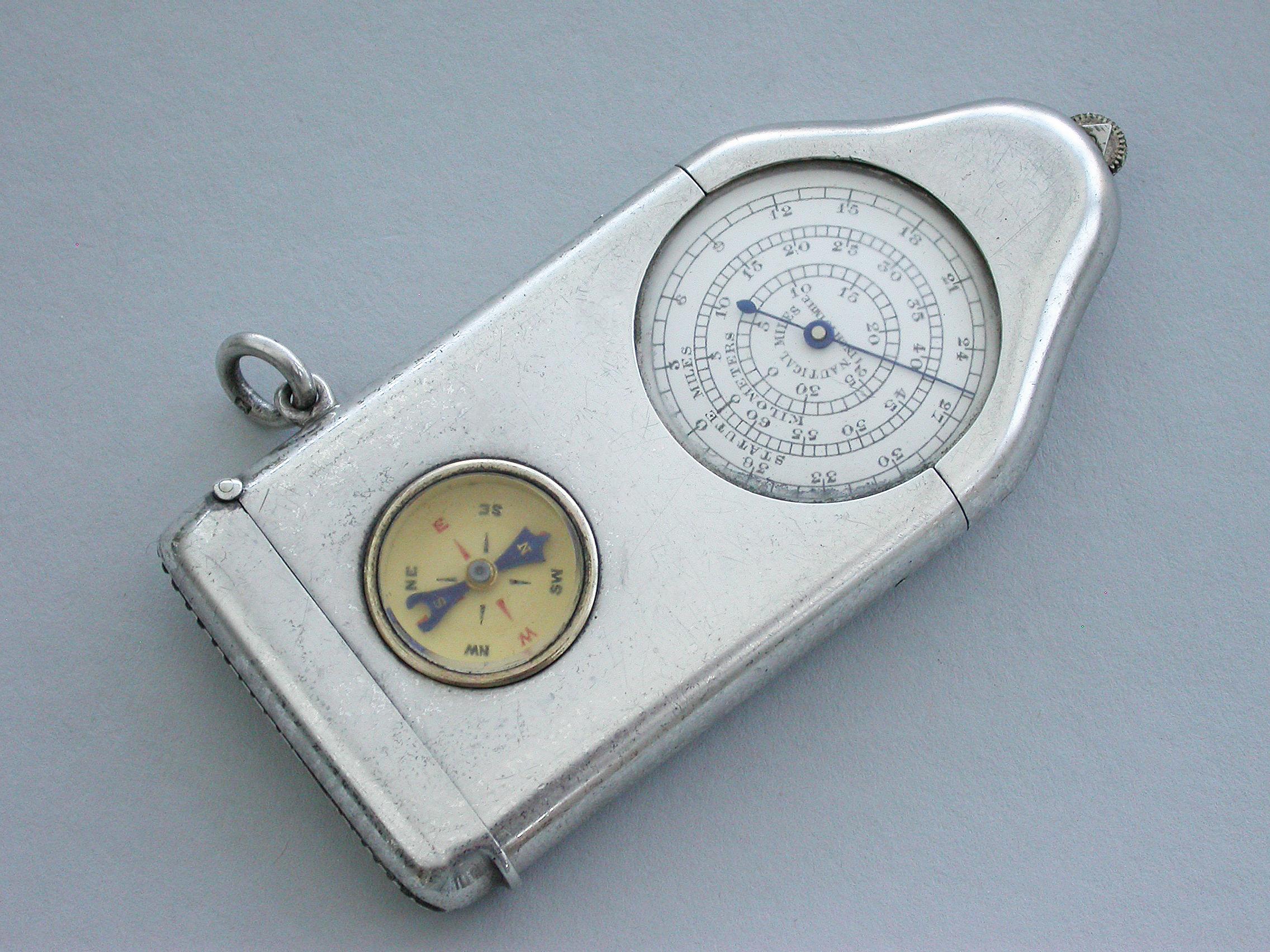 A fine and unusual George V silver Opisometer map measuring tool combined with a Vesta case and a compass, the two glazed enamel dials calibrated for statute miles, kilometers and nautical miles on one side, and half inches to miles and centimeters