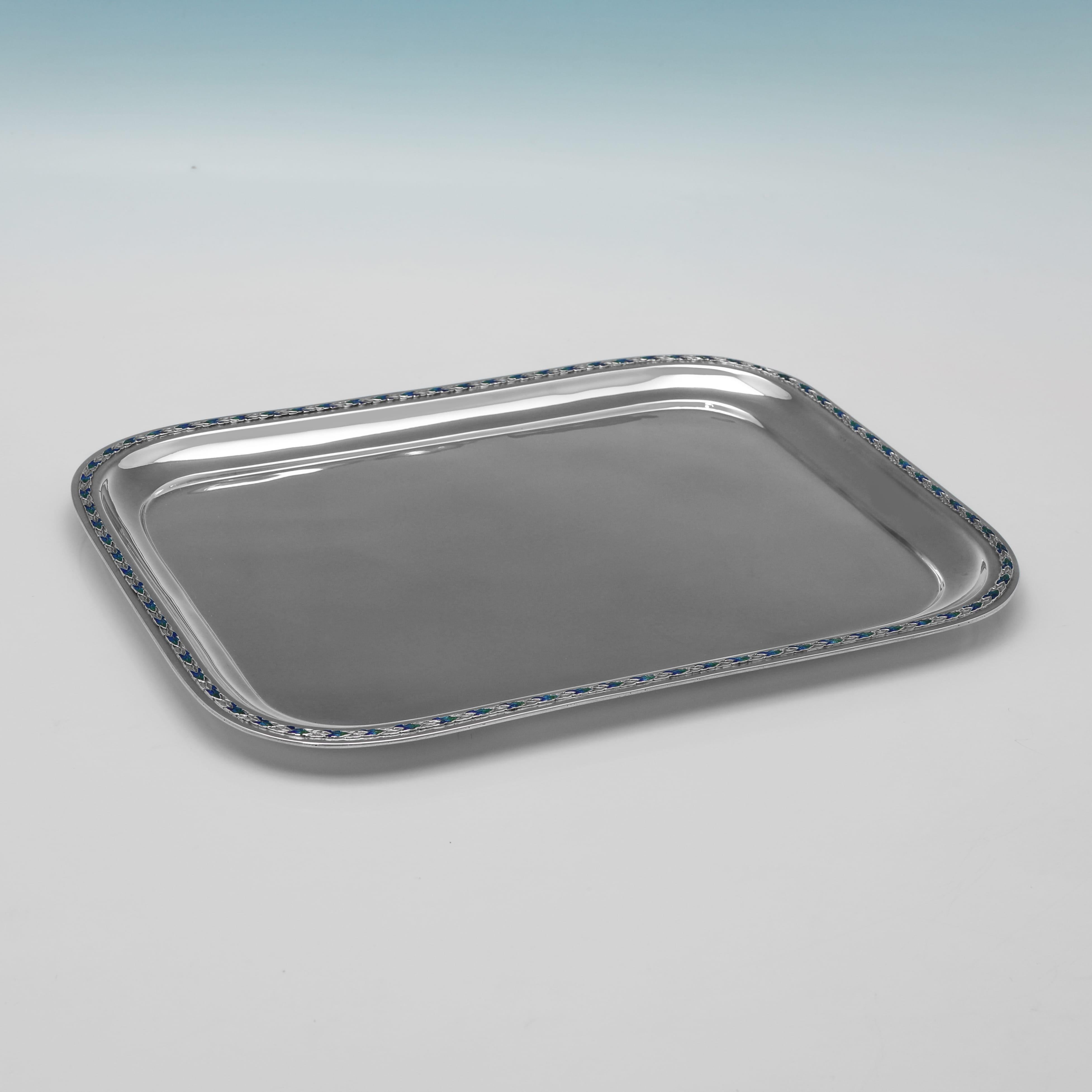 Con il marchio di Birmingham Silver Co. del 1924, questo elegante vassoio da toeletta in argento sterling e smalto di Greene & Co. ha una forma rettangolare con angoli arrotondati ed è decorato con un vivace bordo di smalto blu e verde a forma di