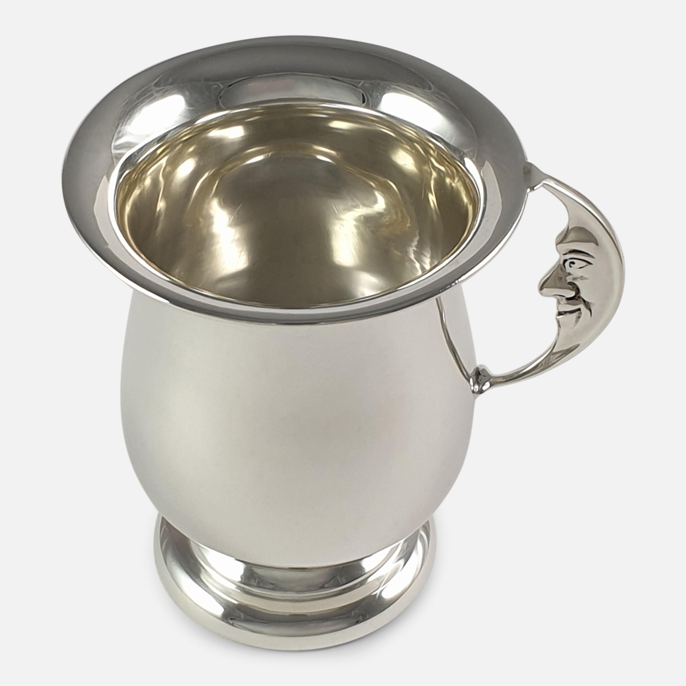A George V sterling silver 'Man In The Moon' christening cup, by Horton & Allday, Birmingham, 1929. The silver cup is of plain baluster form, sitting on a circular pedestal foot. The handle is crafted in the shape of a crescent moon with a 'Man in