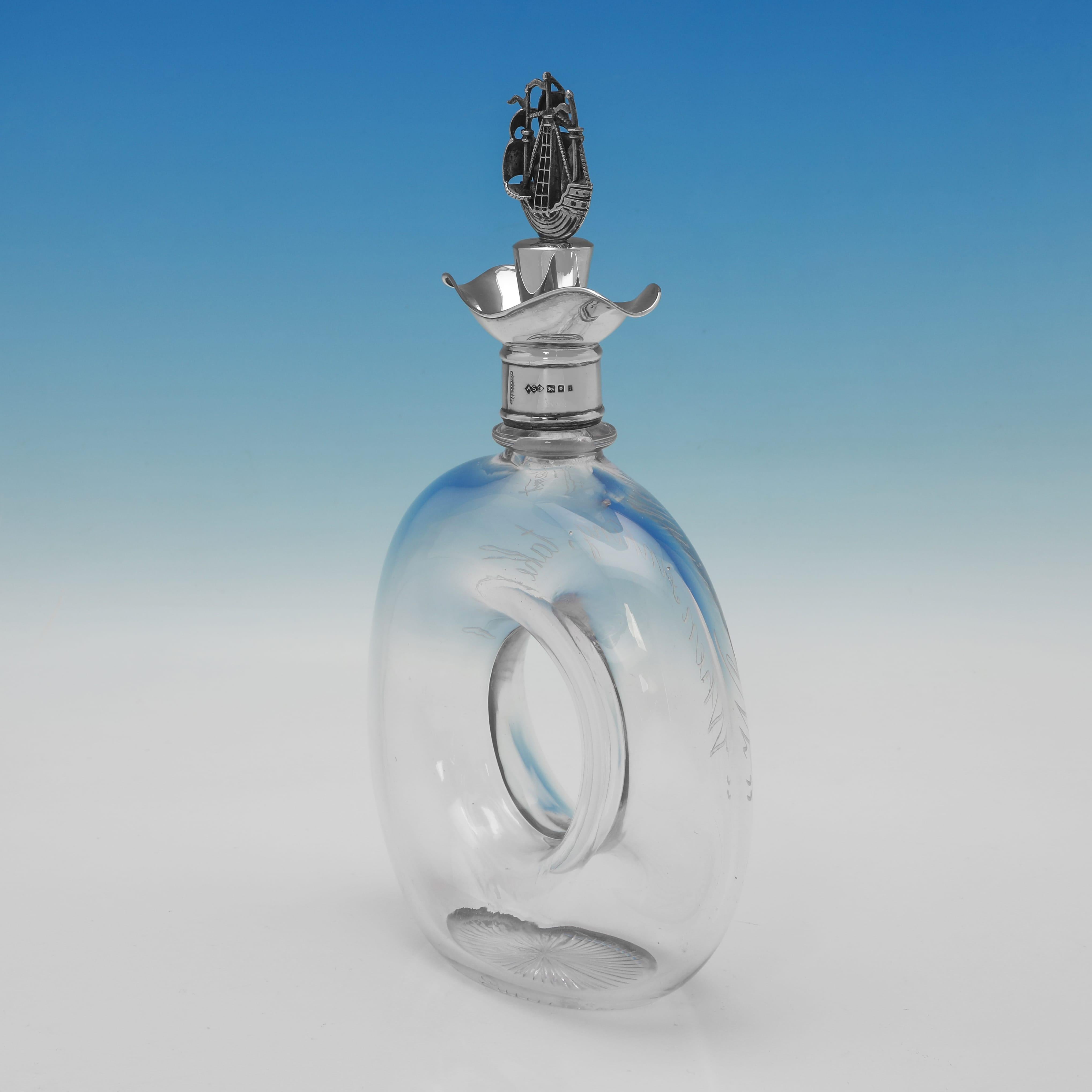 Hallmarked in London in 1924 by Dudley 
Cox this unusual George V sterling silver and glass decanter is of a distinctive ring or 'lifebuoy' form and is hand-engraved with the motto 