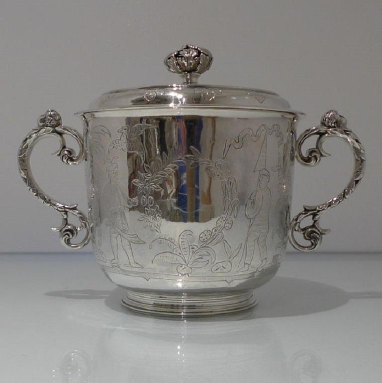 A stunning George V large copy chinoiserie style porringer with elegant scroll handles which are crowned with stylish cherub thumb pieces. The lid is detachable and has additional chinoiserie decoration for highlights.