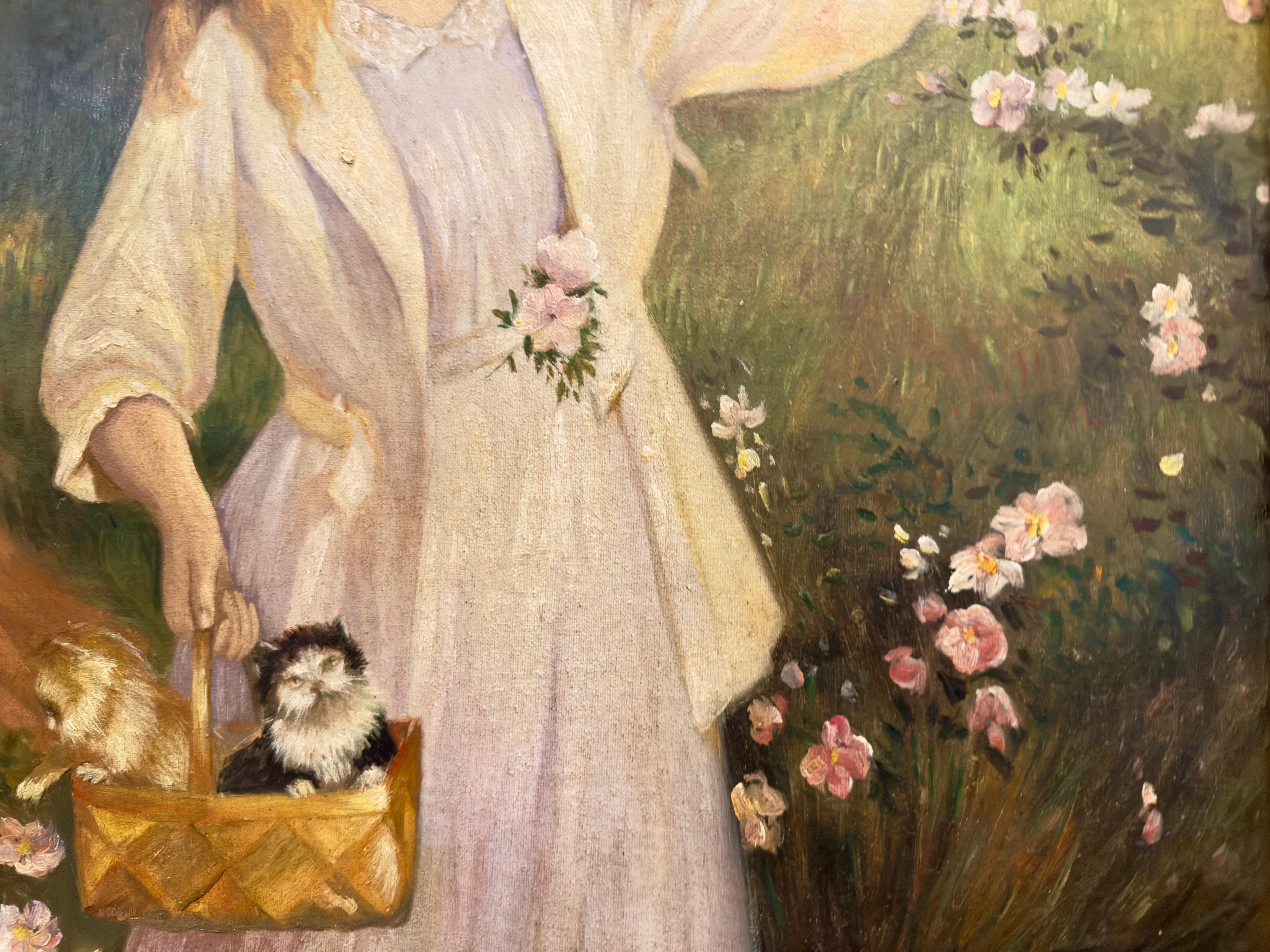 Une jeune femme aux longs cheveux roux, coiffée d'un chapeau de soleil et vêtue d'une robe blanche tient un panier de chatons dans cette peinture à l'huile signée G. V.I.I., d'après ses tableaux figuratifs de la fin du XIXe siècle.  Il a souvent