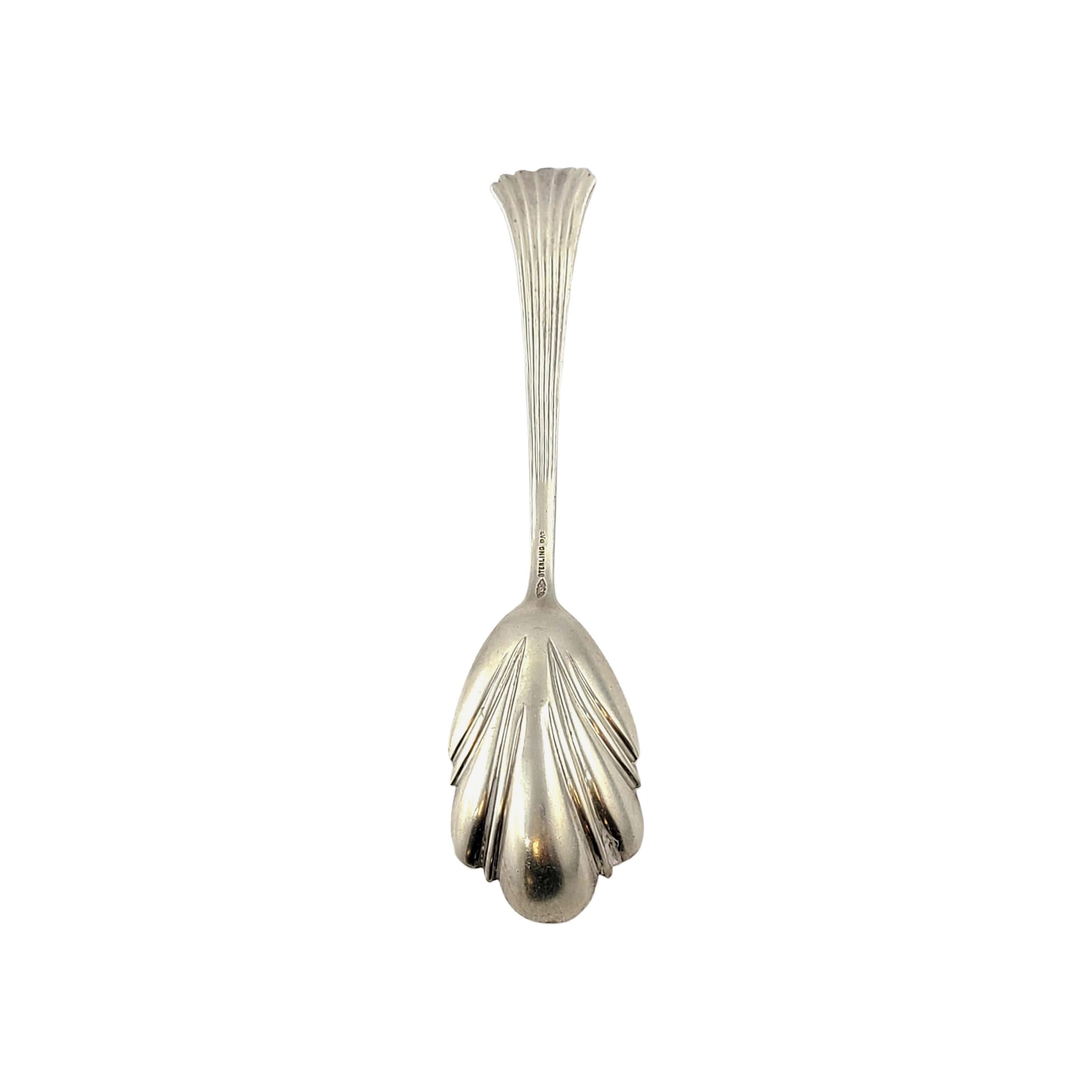 Sterling silver sugar spoon with shell bowl in the No 1 pattern, by George W Shiebler.

George Shiebler is known for his distinctive silver patterns. No 1 is simple yet ornate featuring alternating polished and textured stripes on the handle,