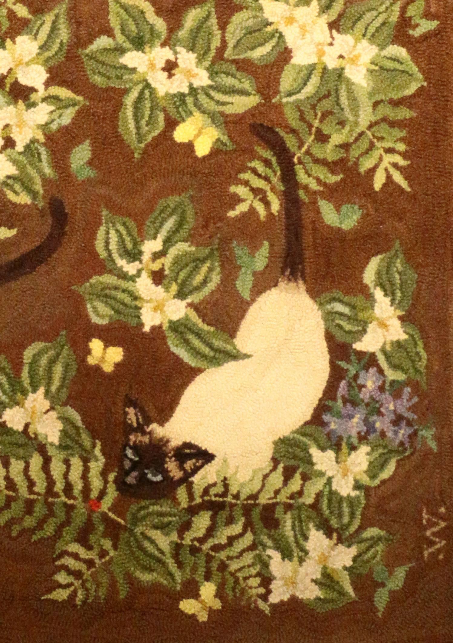 A hooked rug by George Wells Ruggery of Long Island, New York, depicting three Siamese cats amongst ferns and flowers. Each feline is studing a butterfly.
Established in 1920, The Ruggery specializes in creating custom designed hand hooked rugs for