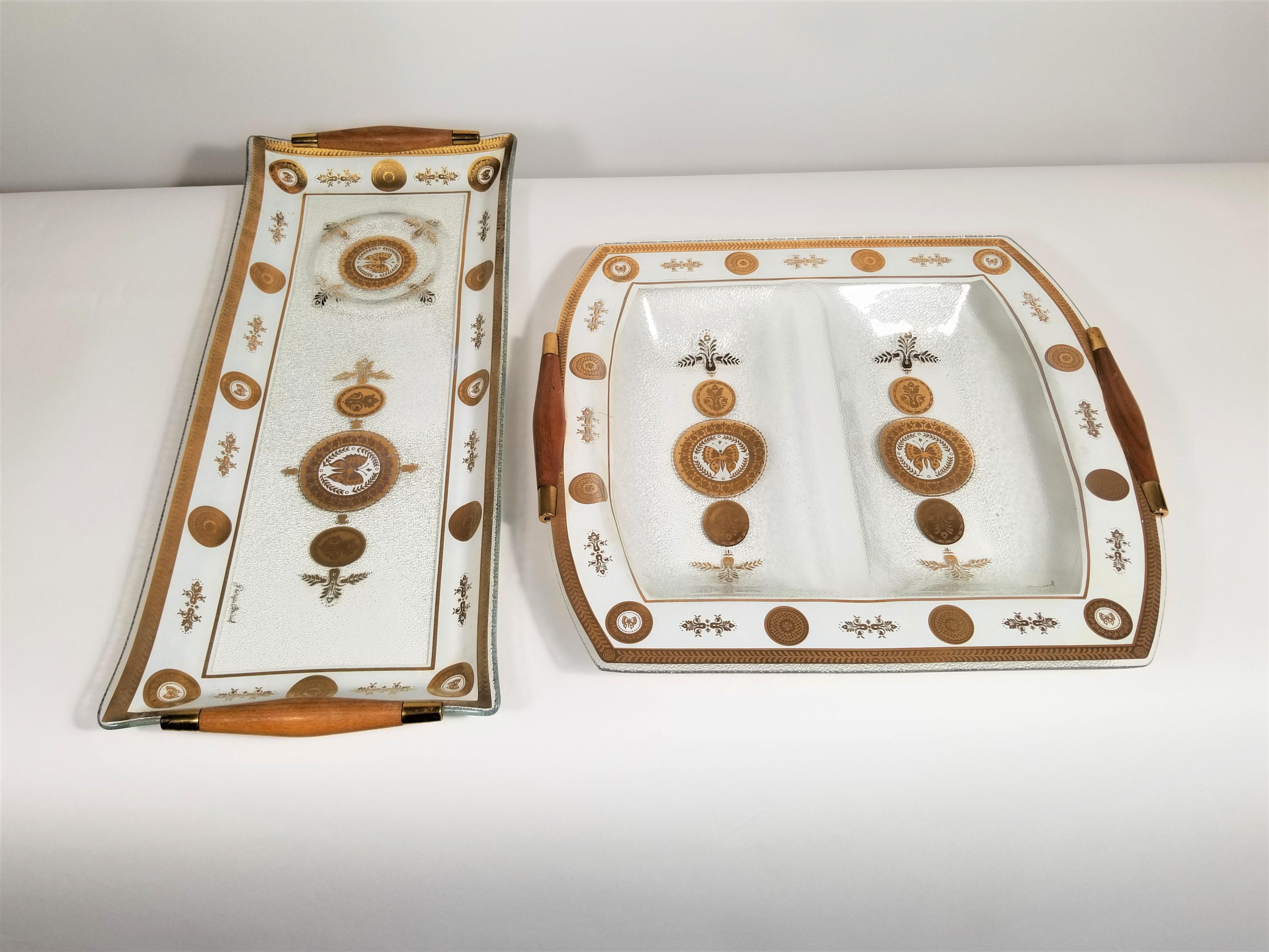 Midcentury 1960s signed Georges Briard Glass Serverware. Set of 2 serving platters or trays. Walnut handles. Gilded accents. Butterfly motif.
Measurements:

Long rectangle:
Height 1.5 inches
Width 19.0 inches
Depth 8.0 inches

Square:
Height 2.0