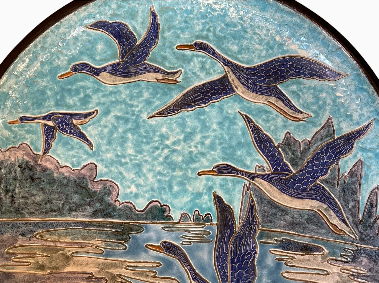 Large ceramic hollow dish representing wild ducks in flight on a turquoise blue background. Signed 