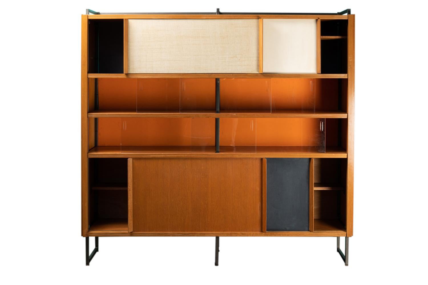 Georges Frydman, attributed to. 

Bookcase in blond oak and black lacquered metal. It opens with colored sliding panels, in veneer and slate. Base and frame in black lacquered metal. The back of the bookcase is made of wood painted in orange,