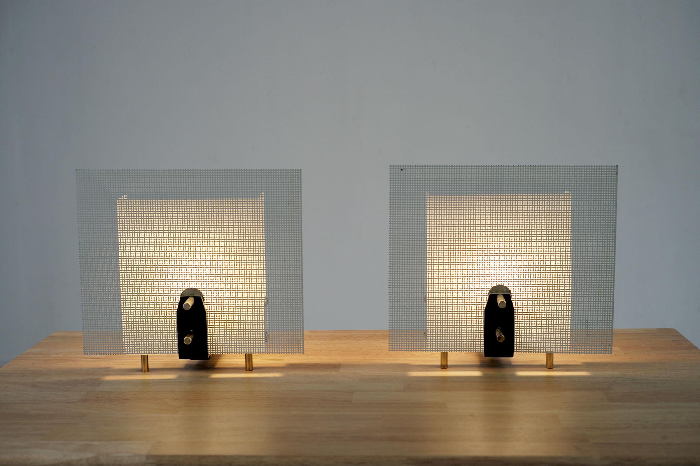 Exceptional pair of table lamps by Georges Frydman, France 1960. T-shaped, the black lacquered metal base rests on 3 cylindrical legs in gilded brass. The double reflector consists of a sheet of white lacquered perforated metal lined with a