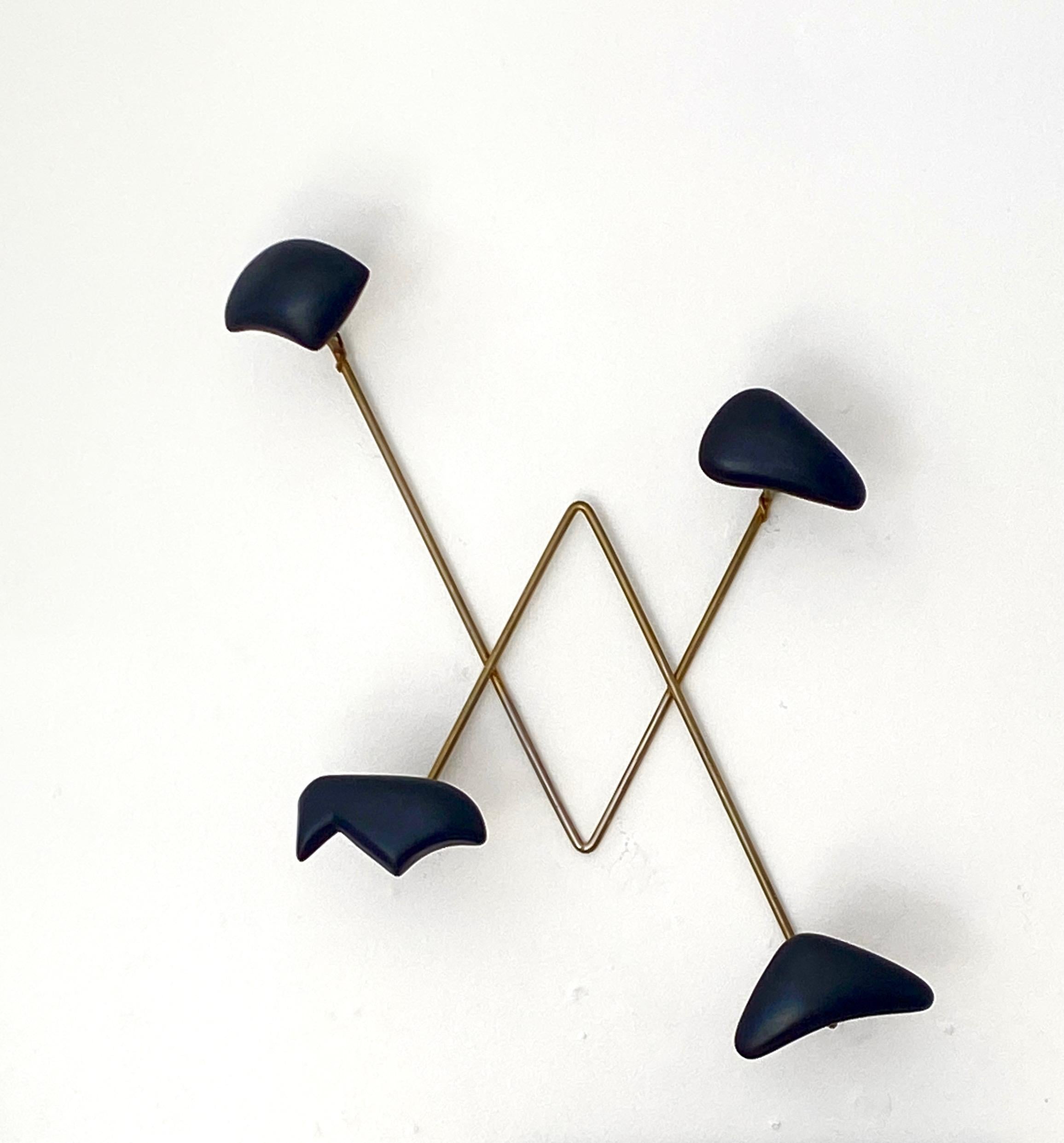 Wall-mounted coat or hat rack by Georges Jouve, produced by Marcel Asselbur, France, circa 1950. 

Glazed matte black stoneware forms, with a brass frame. Four abstract Jouve ceramic forms that can be used as a coat or hat hook. Excellent condition