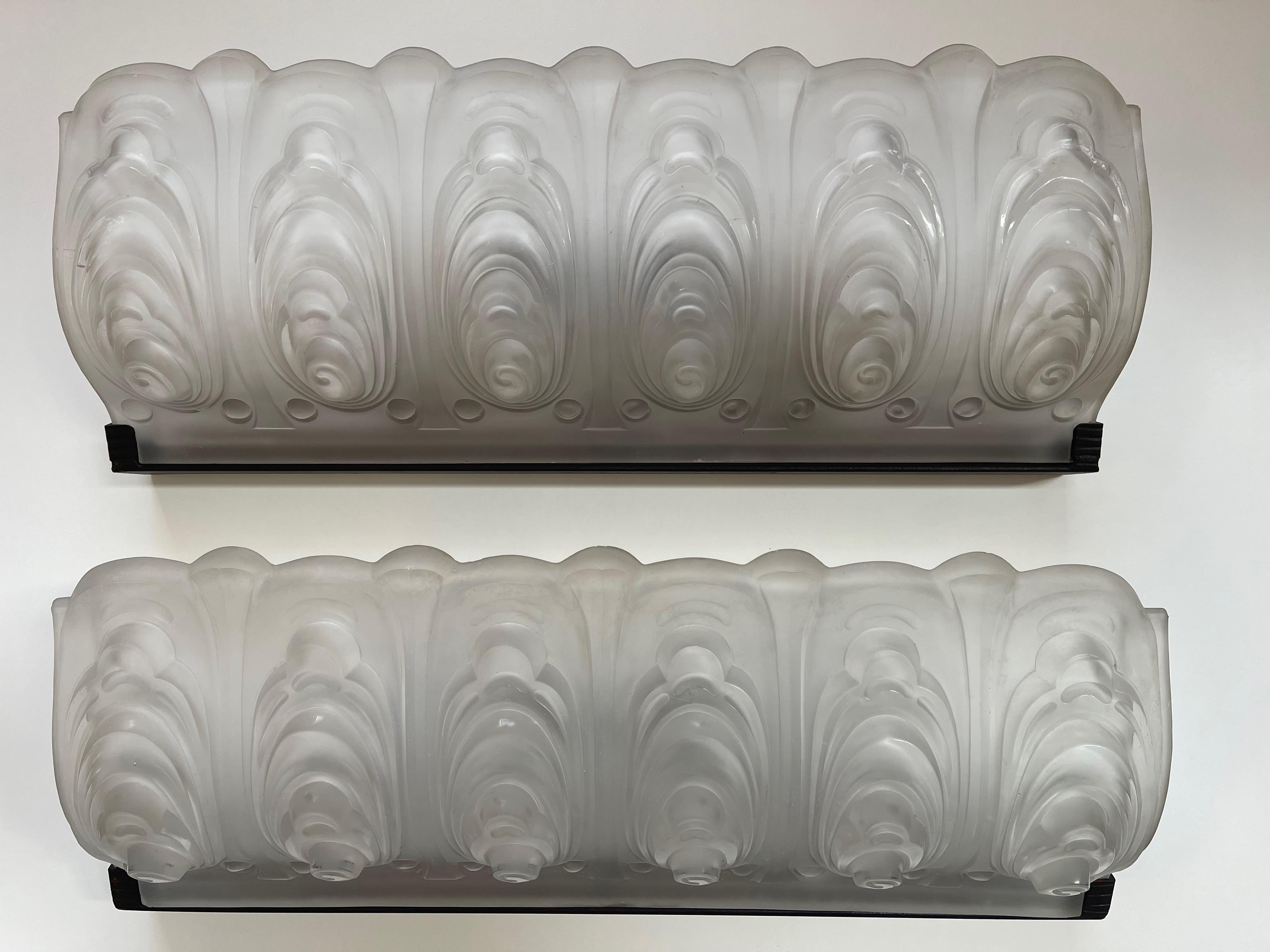 Large pair of art deco sconces attributed to Georges Leleu in molded glass, hammered iron frame.
In very good condition and electrified.

Measures: Width: 50cm
Height: 19.5cm
Depth: 11.5cm
Weight: 8 Kg.