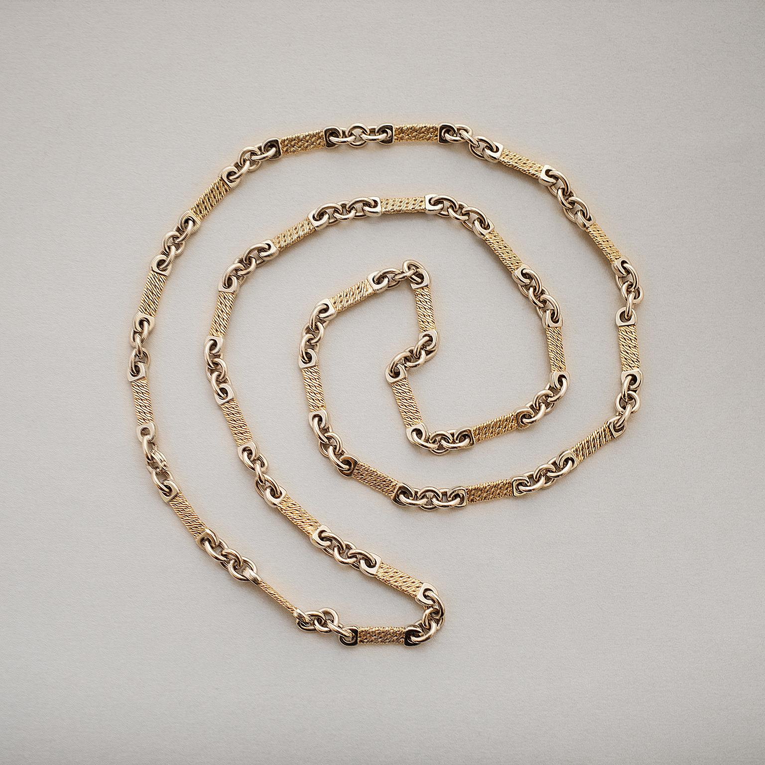 A bi-color 18 carat gold long chain with yellow gold textured flat links with white gold polished ends, master mark: Georges Lenfant, France circa 1970.

weight: 79 grams
length: 81 cm
width: 5 mm