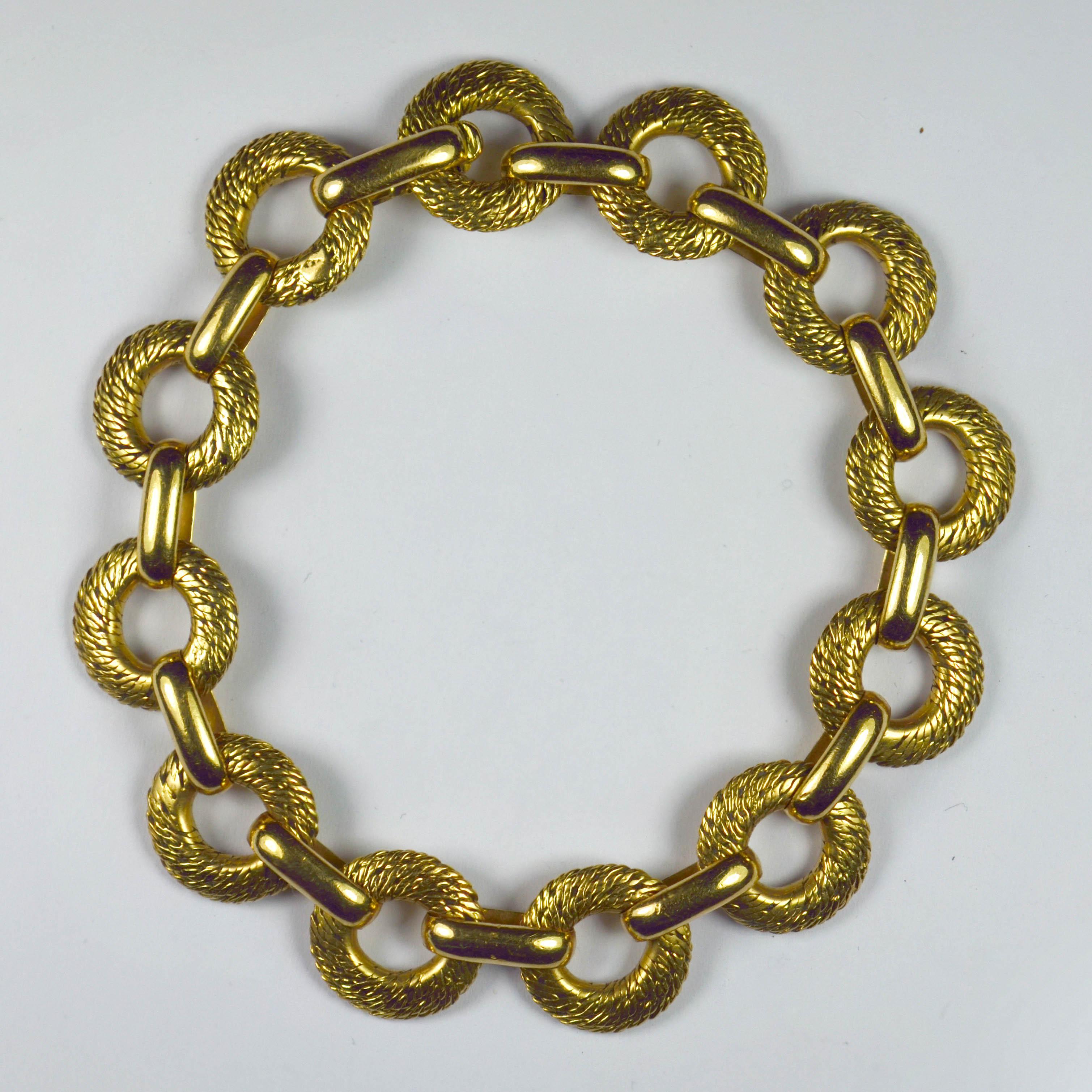 A French 18 karat yellow gold link bracelet by Georges L'Enfant, with 12 textured circular links connected by 12 smooth yellow gold bar links. Stamped with the eagle's head mark for French manufacture and 18 karat gold, with a partial maker's mark