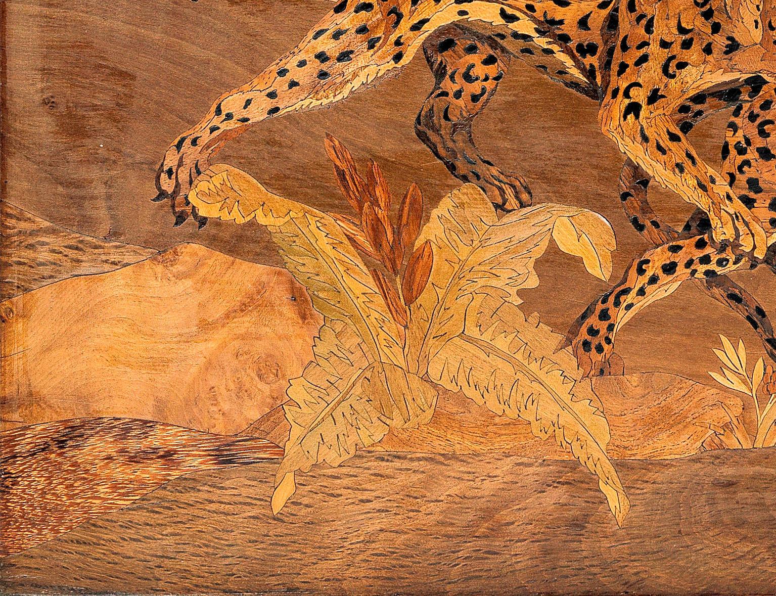 An exceptional marquetry panel by Georges Lucien Guyot, derived from his explorations and observations in the wilds of Africa. This rare marquetry panel depicts two Cheetahs fighting in a verdant landscape, picked out in exotic timbers including