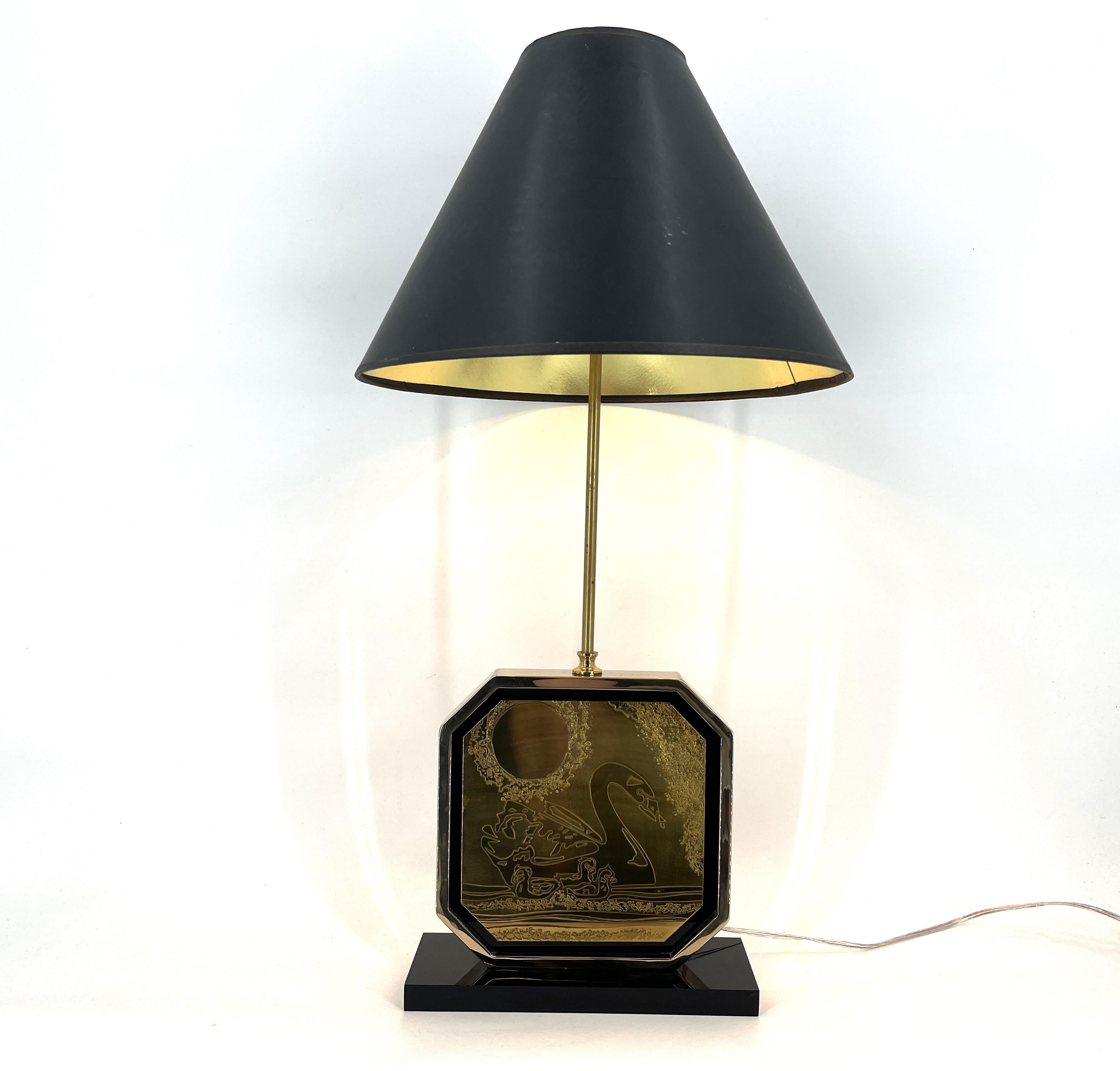 Lampe de table Hollywood regency conçue et fabriquée par Georges Mathias dans les années 1970.

La table se compose d'une base laquée noire, d'un cadre en laiton 23kt contenant l'œuvre d'art gravée et d'un abat-jour doré.

Toutes les lampes ont été