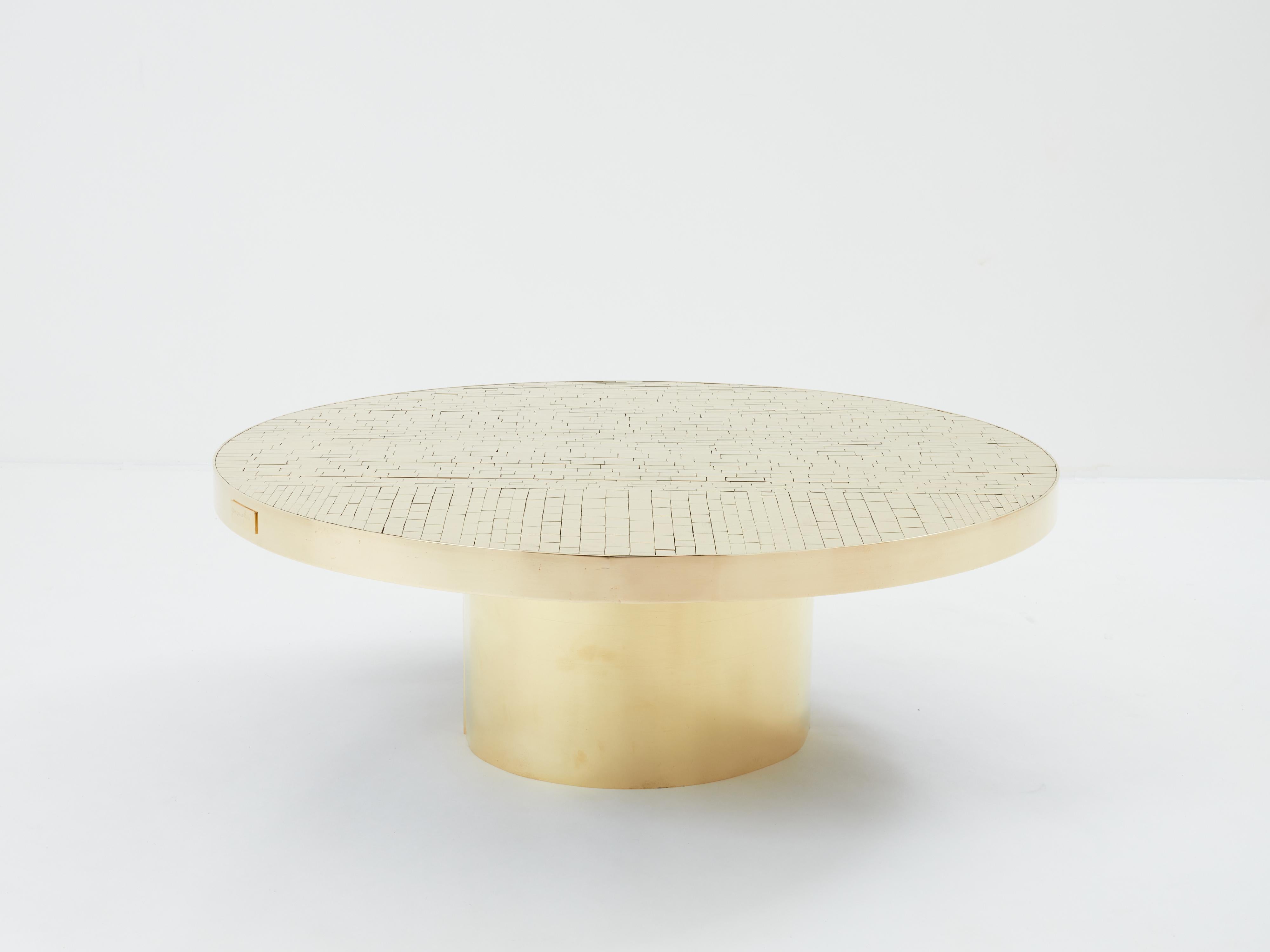 Il s'agit d'une table basse ronde belge unique, signée par Georges Mathias et produite à la fin des années 1970. La table présente un étonnant plateau en mosaïque composé de pavés de laiton poli, entouré d'un cerclage en laiton comportant une plaque