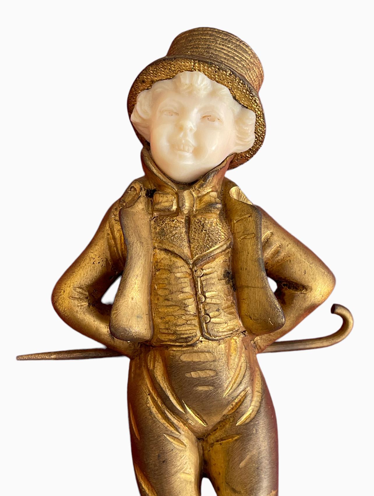 Chryselephantine representing a young man dressed in a top hat, his hands behind his back holding a walking stick. Circa 1910. This bronze is signed 