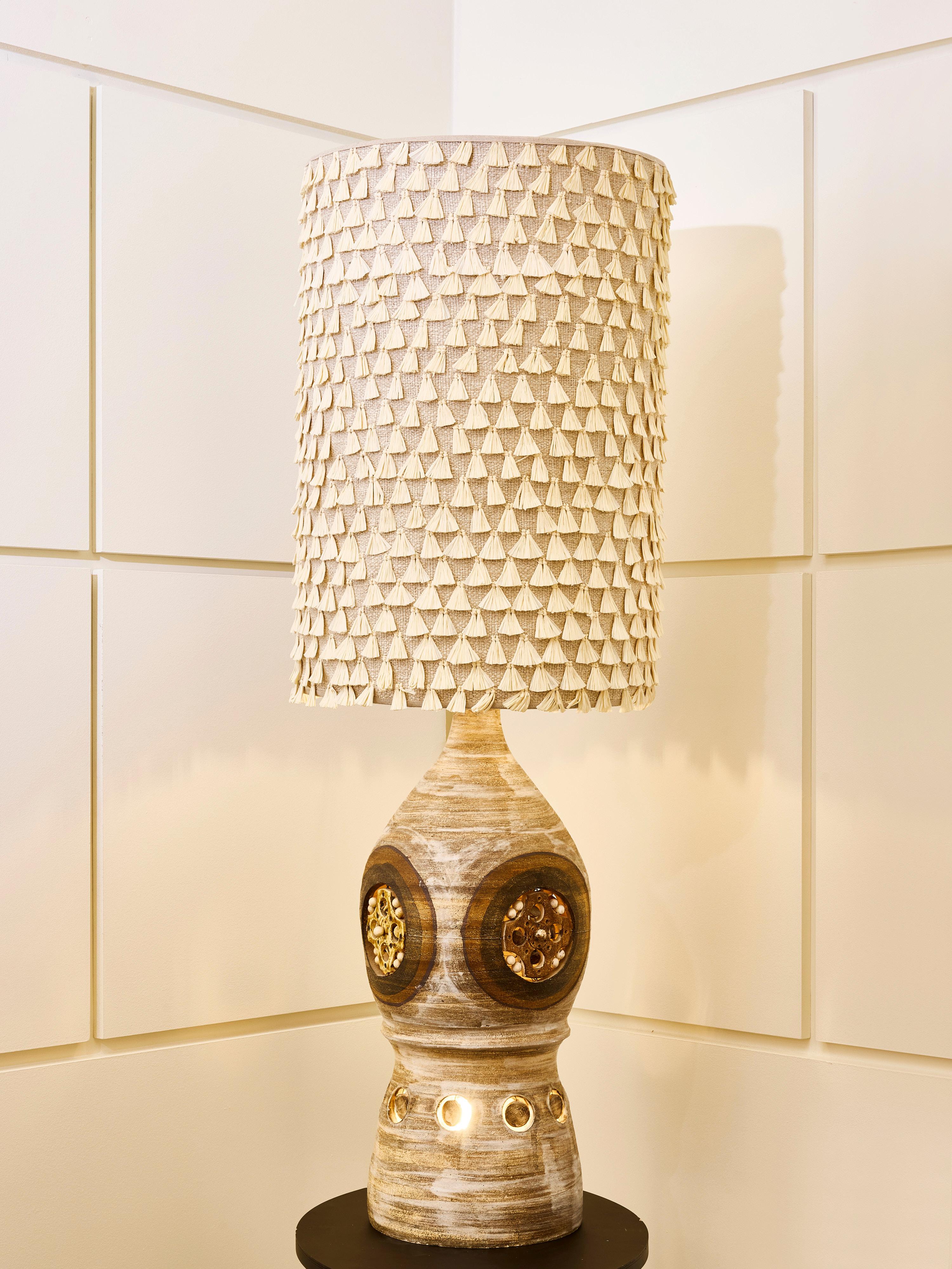 Lampe de table de l'artiste français Georges Pelletier, dotée d'un design sculptural saisissant qui allie le travail de la terre à une texture moderne. La base est en céramique avec une forme arrondie, semblable à celle d'une bouteille, et présente