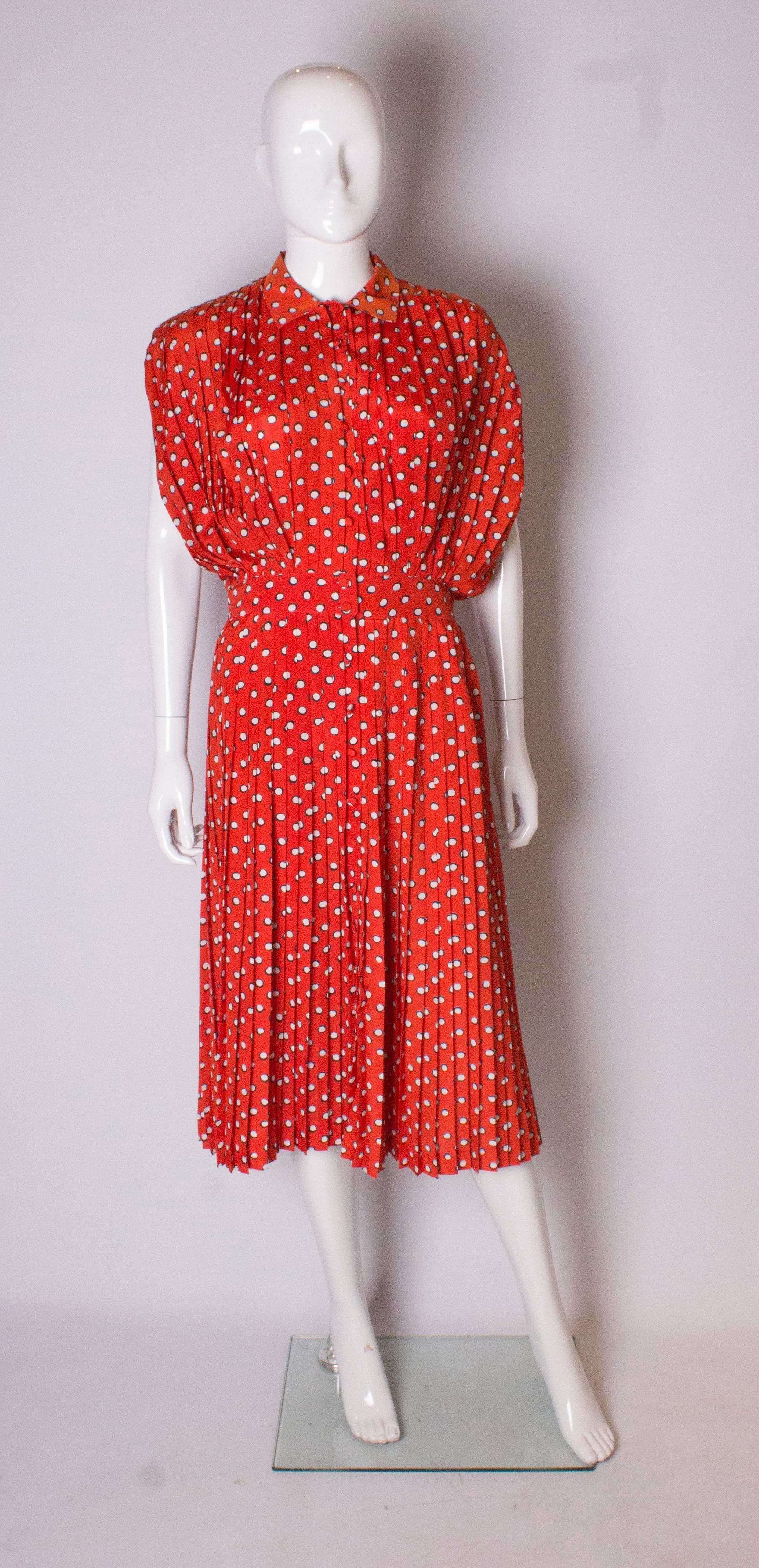 A great dress by Georges Rechs. The dress is pleated wiht a button front opening. The fabric has a red background with blakc and white spots.