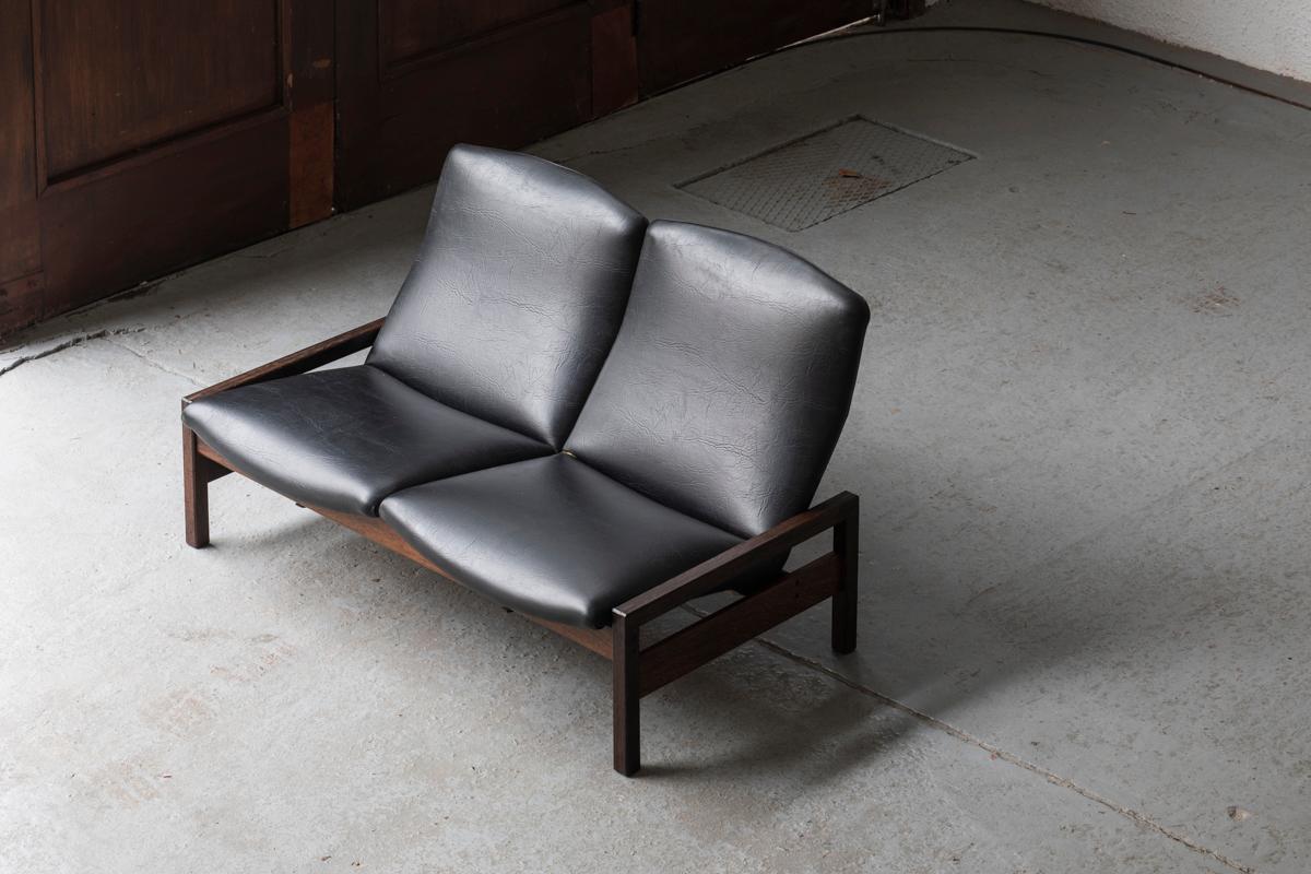 2-Seater designed by Georges Van Rijck and produced by Beaufort in Belgium around 1960. The wengé frame supports both black seats, which can be easily clicked in and out. The skai upholstery shows some cuts, as shown in the pictures. Apart from some