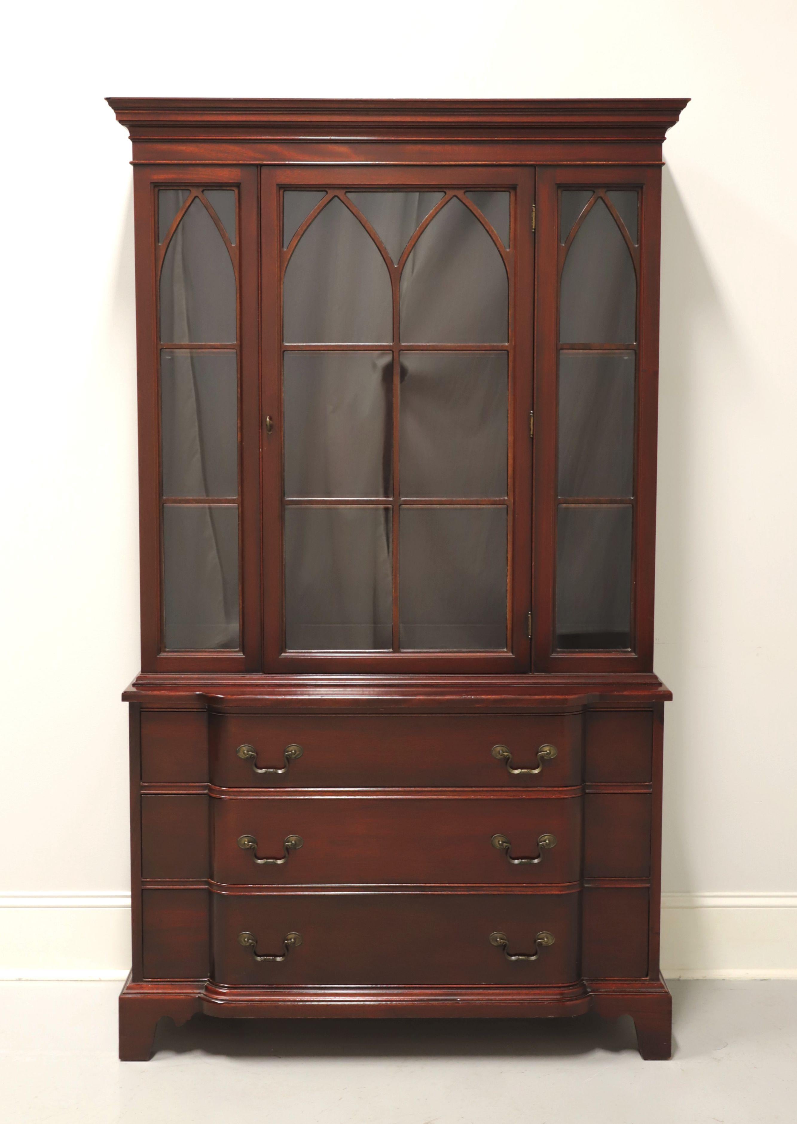 A Georgian style china cabinet by Georgetown Galleries. Solid mahogany with brass hardware, crown molding at top, bowfront lower cabinet and bracket feet. Upper cabinet has one center glass door with flanking side panels, fretwork over glass, and