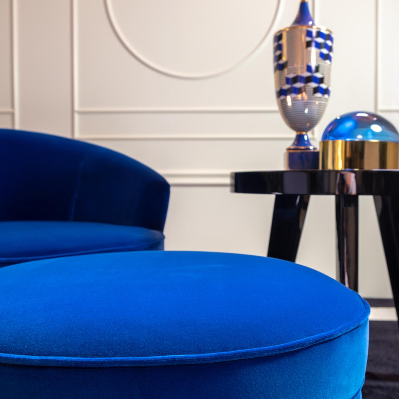Designed by Domenico Mula as matching accessory for the Georgette Armchair, this pouf's retro-inspired look will fit elegantly in both classic and modern interiors. The round shape showcases a plush velvet fabric cover in cobalt blue with vertical