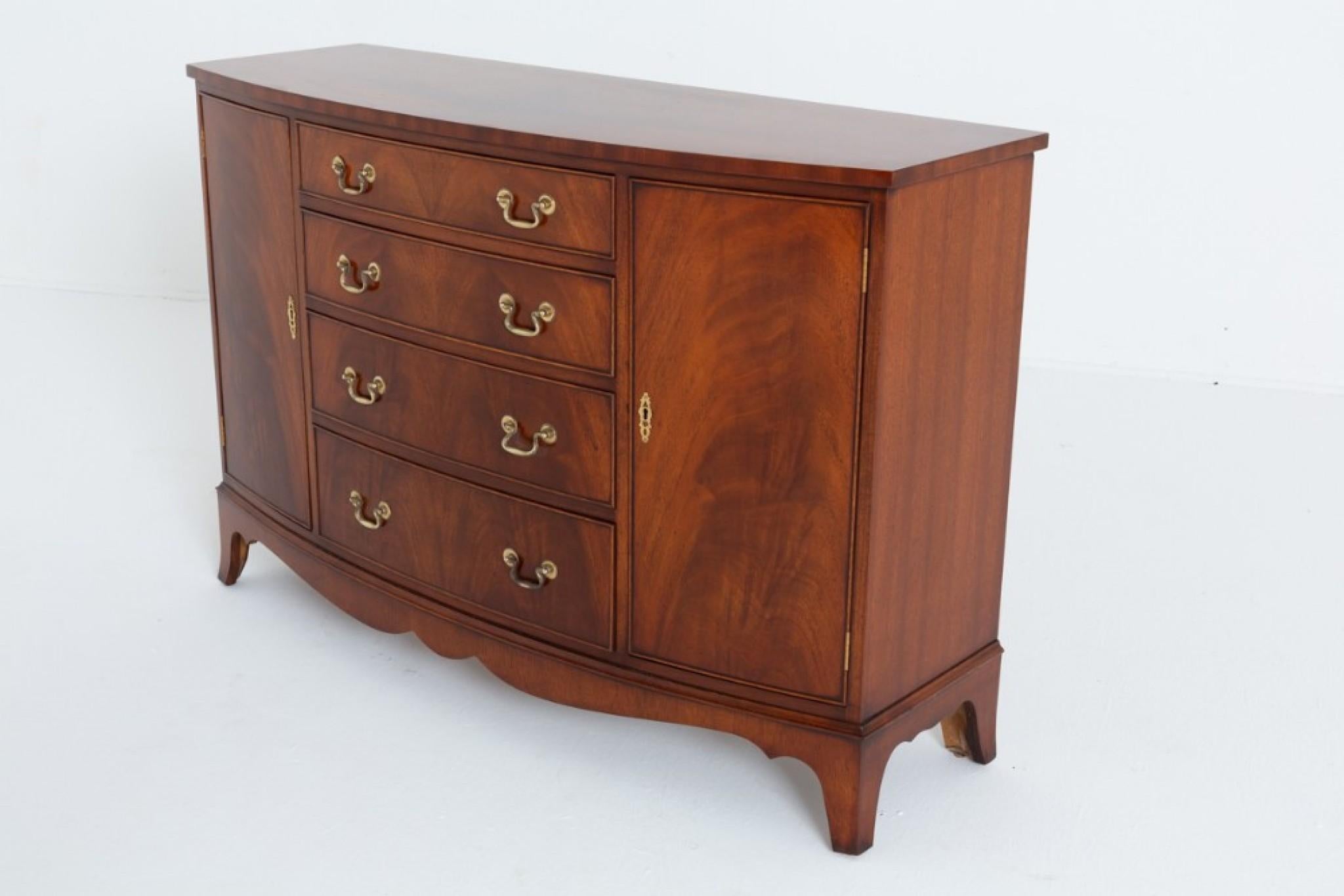 Georgian Revival Mahogany Bow Sideboard.
This Elegant Sideboard Has 4 Graduated Mahogany Lined Drawers which Feature Brass Swan Neck Handles.
Circa 1920
The Drawers are Flanked by Cupboard Doors which open to Reveal Shelving.
The Sideboard is Raised