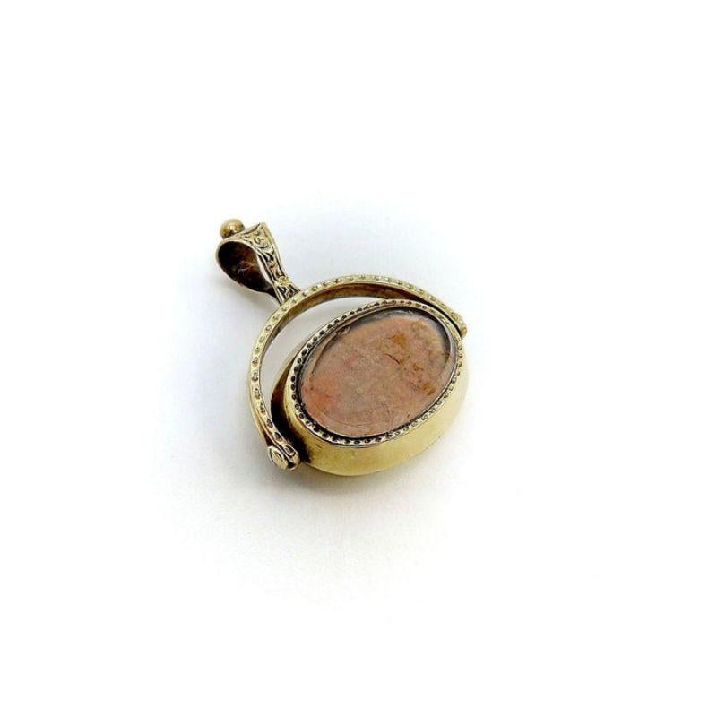 Se trata de un colgante-aleta de reloj georgiano de oro de 10 quilates, fantásticamente elaborado, que presenta un eslabón giratorio ovalado con ágata engastada en bisel por un lado y un cristal de roca pulido por el otro. El ágata moteada es de dos