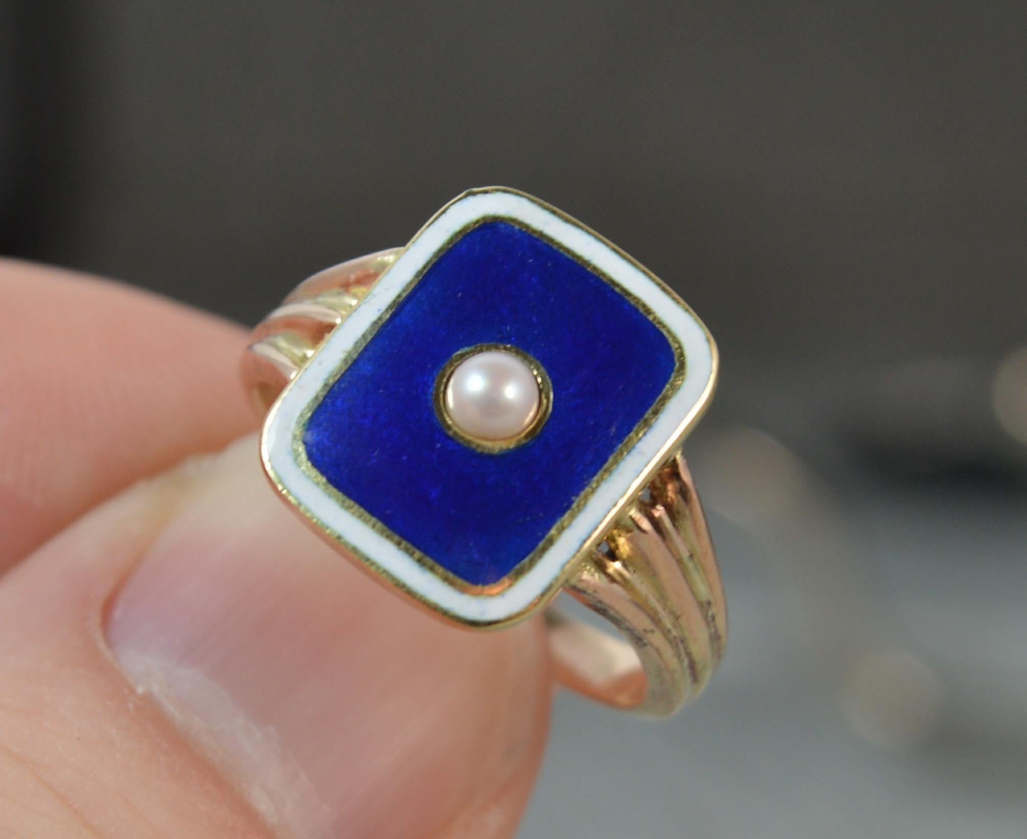 A very fine Georgian period ring. Circa 1790.
Designed with a rectangular head of low profile. Set with a pearl to the centre of a blue enamel surround and white enamel border.
Pierced shoulders and solid 12 carat gold shank.
11mm x 13.5mm