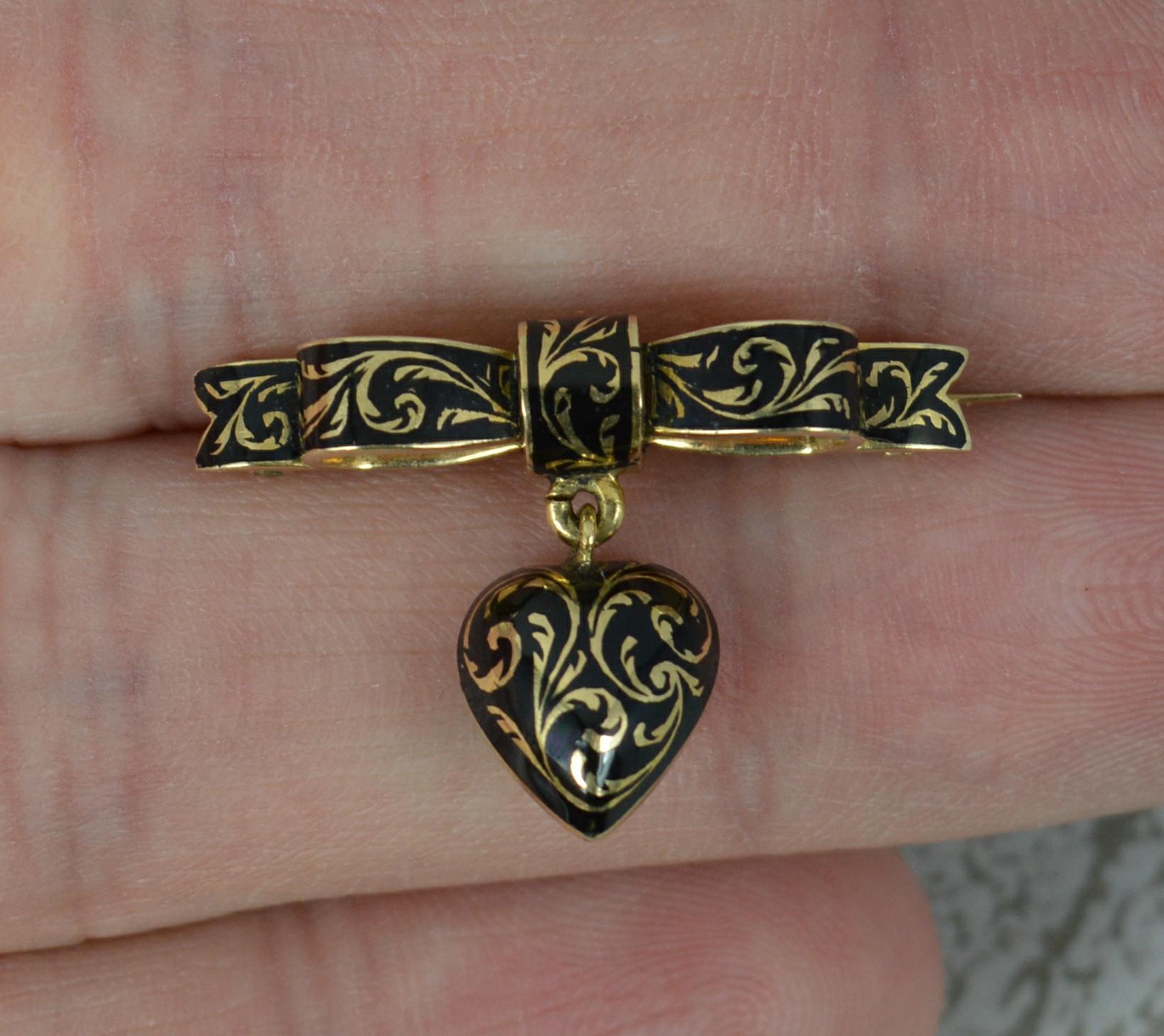 A stunning and highly unusual Georgian mourning brooch.
Solid 15 carat yellow gold example.
Ribbon or bow design to the top with a heart drop below.
Black enamel with scroll design throughout and a locket section to reverse.

CONDITION ; Very for