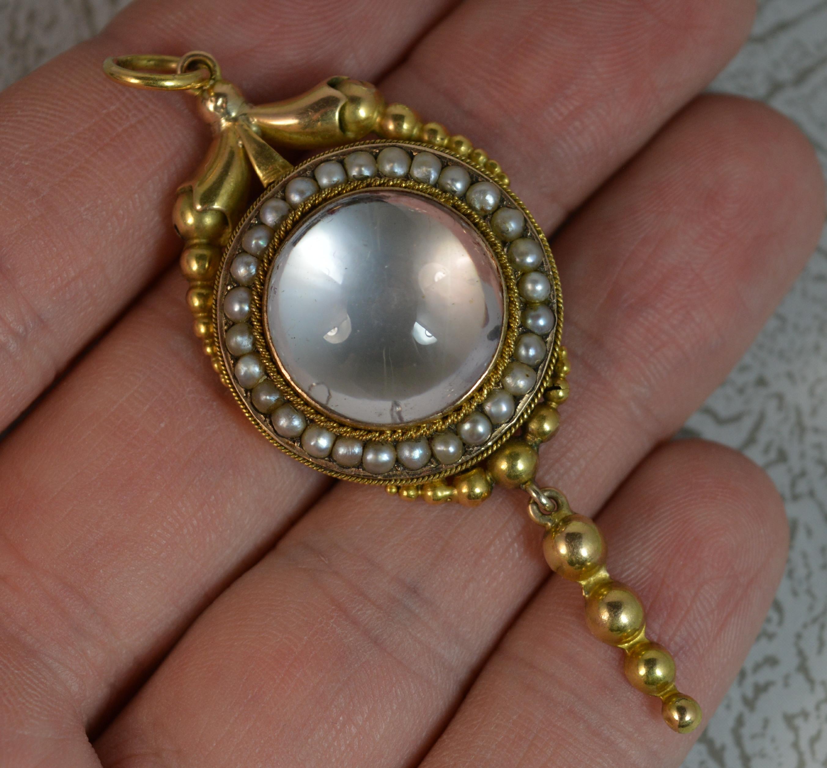 A rare true Georgian period pendant, circa 1820.
Solid 15 carat yellow gold example. 
Gold ribbon like design to the top with a circular cluster comprising of large circular rock crystal to the centre with seed pearl border surround. Complete with