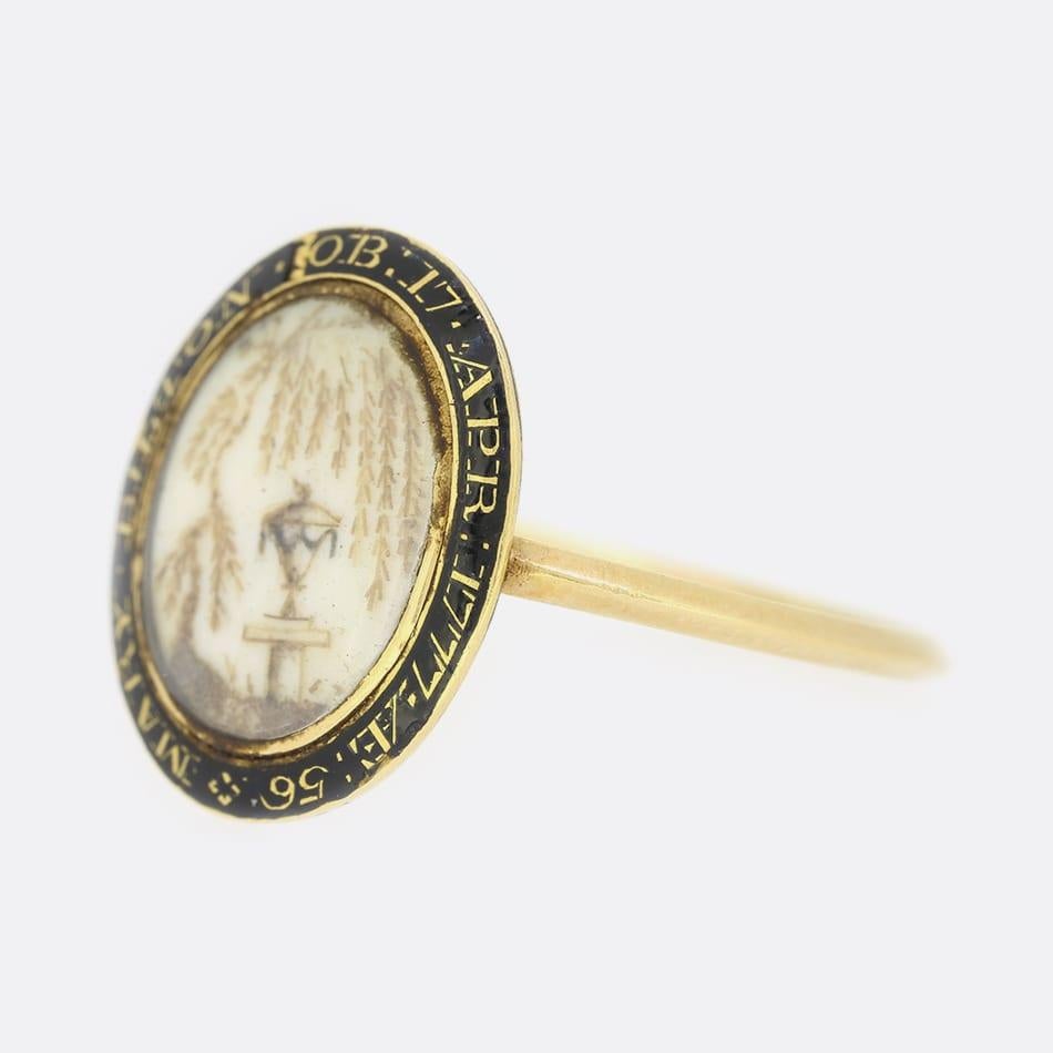 This is a wonderful 18ct yellow gold Georgian mourning ring. The face of the ring features a wonderful hair work urn which sits underneath a willow tree and is set on an ivory plaque. Surrounding the miniature is a black enamel border with the words