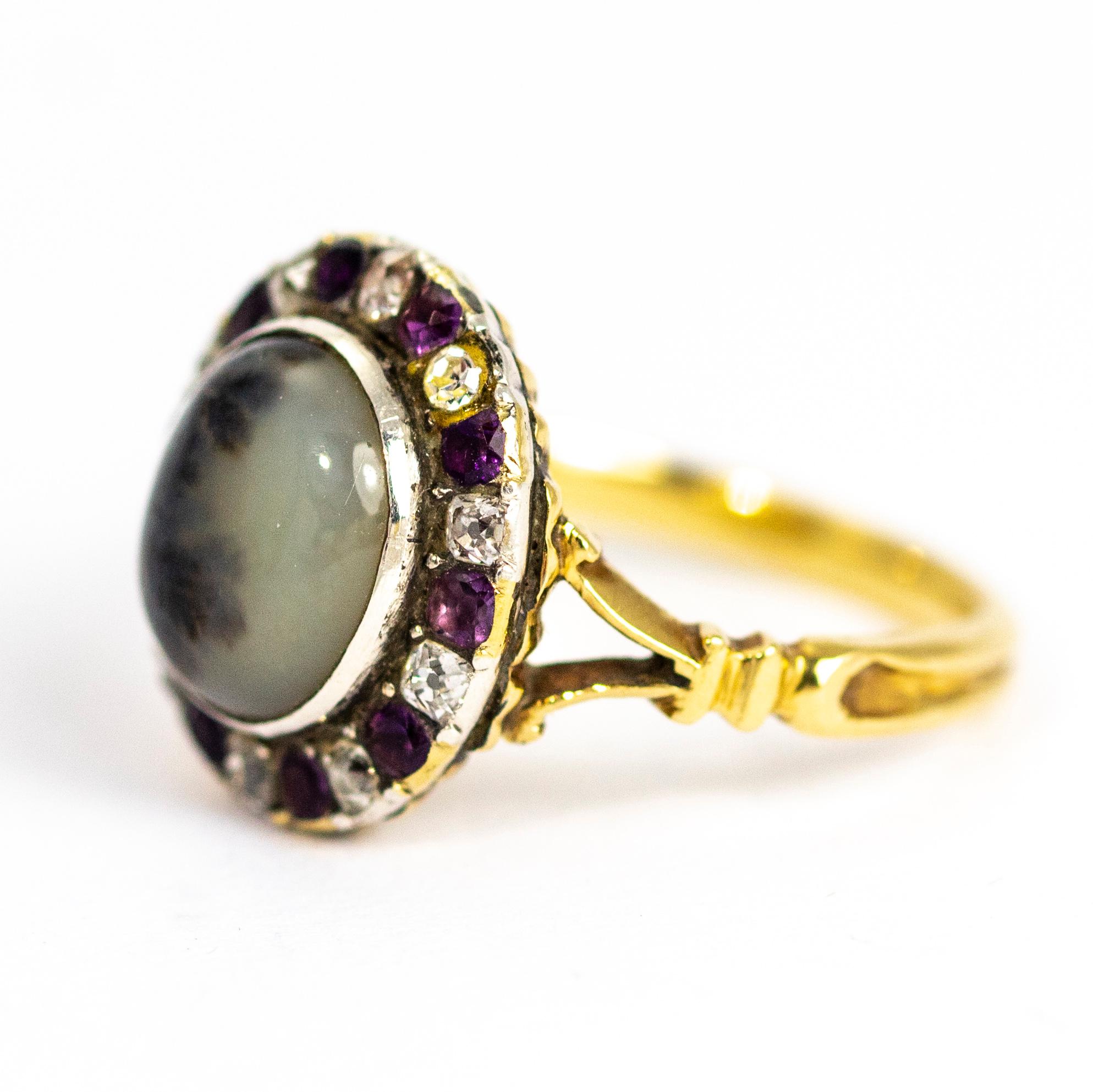This exquisite late Georgian ring is set with a superb dendritic agate cabochon. The agates wonderful colouring resembles a group of trees silhouetted agains a twilight sky. Surrounding the central stone is a halo of alternating old mine cut