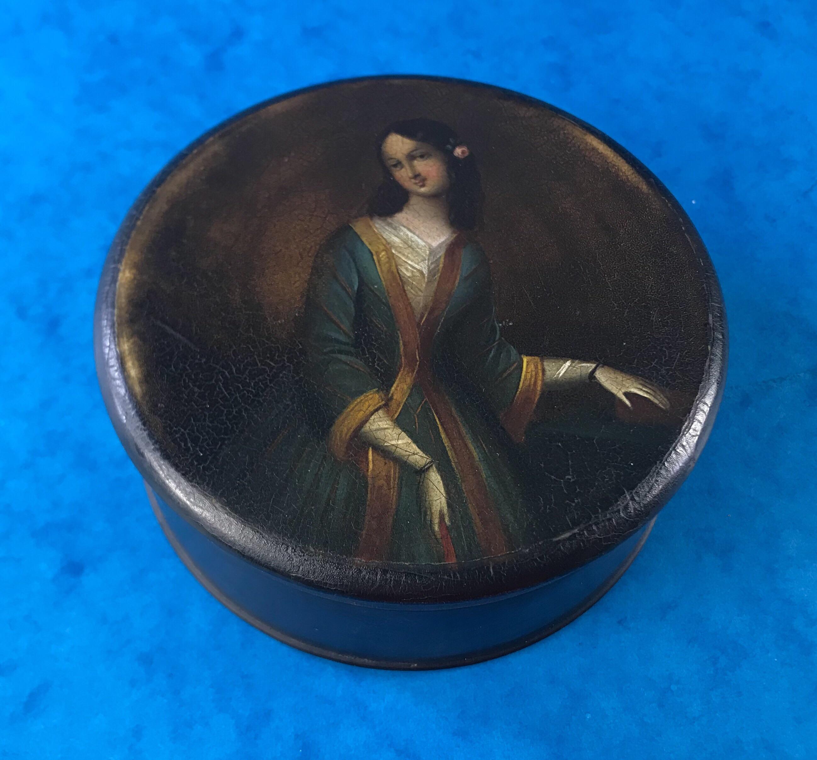 A Georgian 1820 painted papier-mâché table snuff box of a lady in blue white and gold, it measures 11.5 by 12 and stands 5cm high.
    