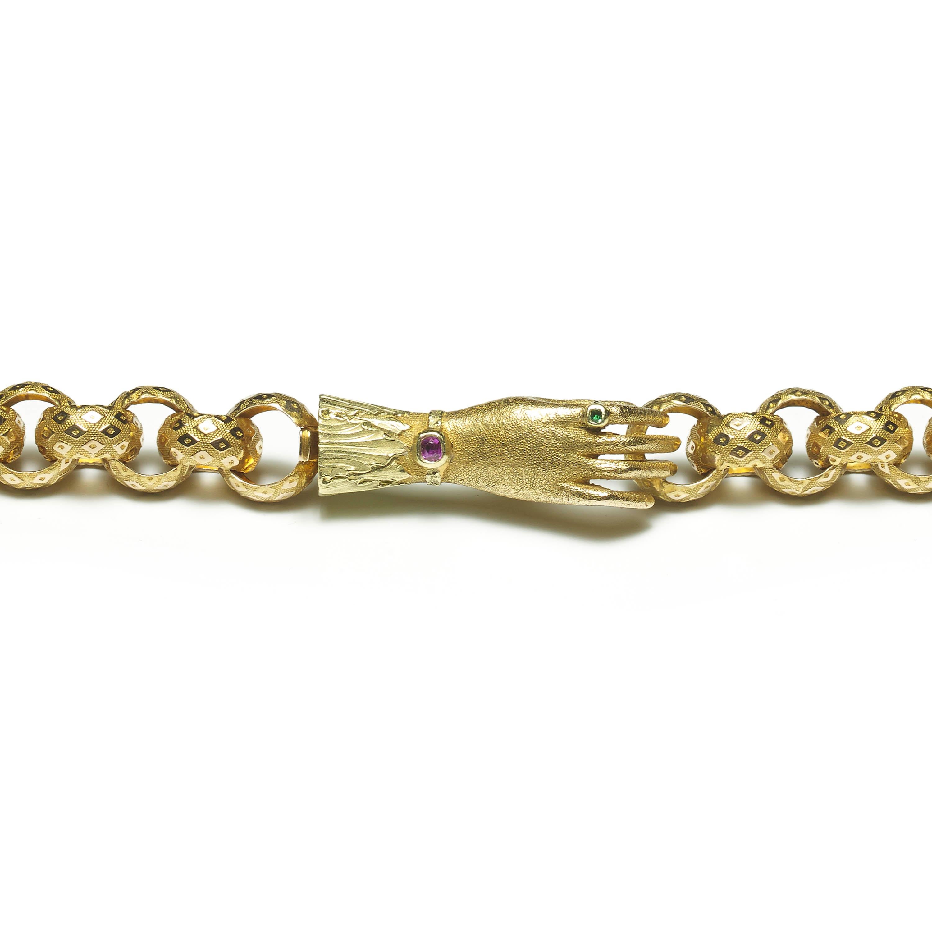 A Georgian long chain, in 18ct yellow gold, comprised of round links with diamond patterns, terminating in a hand-shaped clasp, the hand with ruby bracelet and emerald ring details, with the original fitted case. Circa 1830.
