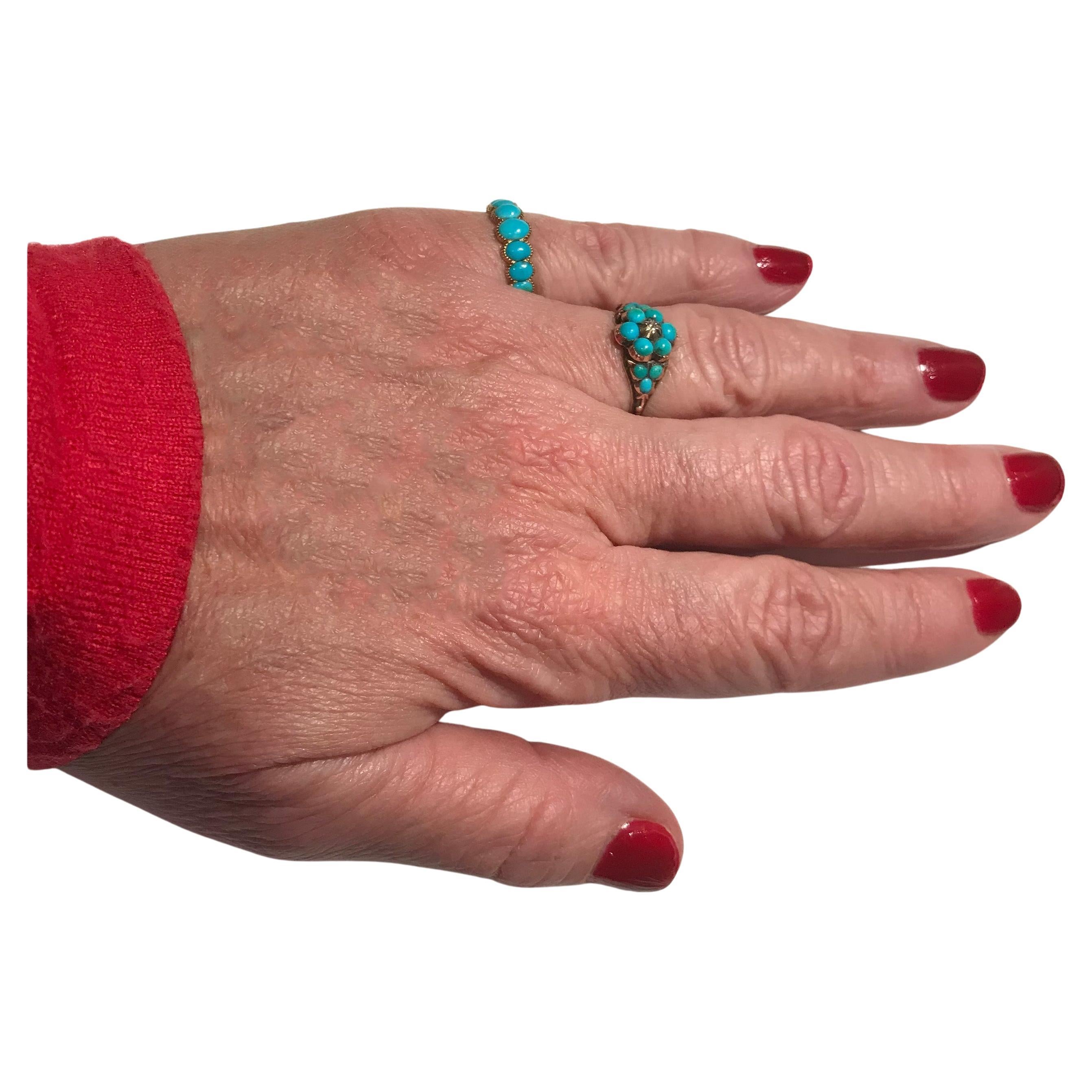 Late Georgian half hoop ring with 7 well matched turquoise stones set en cabochon with the largest turquoise in the center and each stone graduated in size, individually hand carved in a floral chased band. The borders of each stone are crimped, an