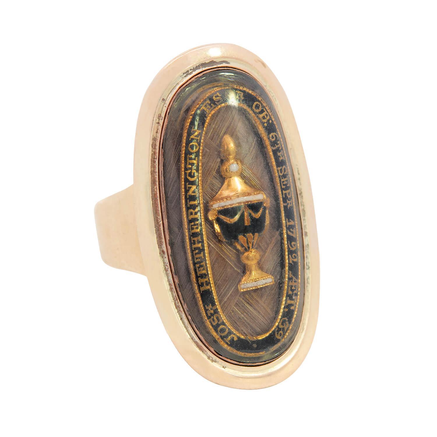 An exceptional and unusual memorial urn ring from the Georgian (ca1780) era! Crafted in 18k yellow gold, the ring features a large, ellipse-shaped centerpiece. The centerpiece of the ring features a small urn motif, which is decorated with black and