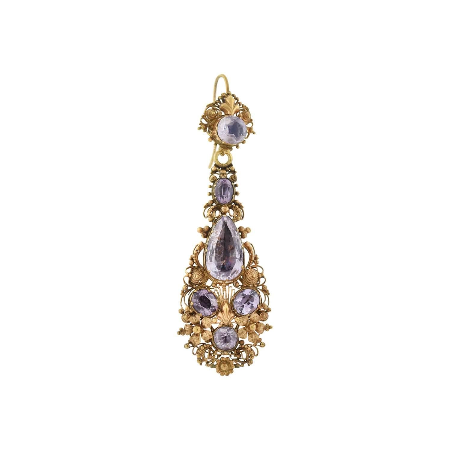 A gorgeous pair of earrings from the Georgian (ca1850s) era! Crafted in 18kt yellow gold, the earrings begin with an oval-shaped light purple amethyst stone, set in a closed-back East-to-West style. Feminine cannetille wirework and small gold beads