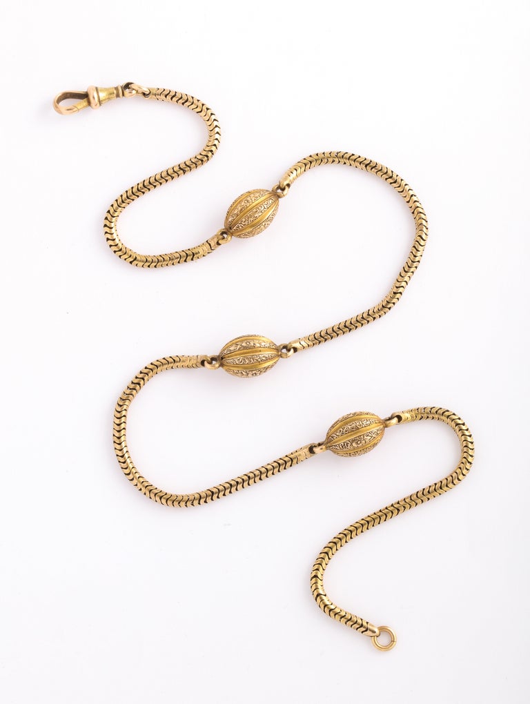 A smooth 18 Kt snake chain from the Georgian era has beautiful melon ball links here and there. The oval links are covered with roses and leaves and comforting to the touch. The chain is 19 1/2 inches long, a perfect length for inside a shirt or on