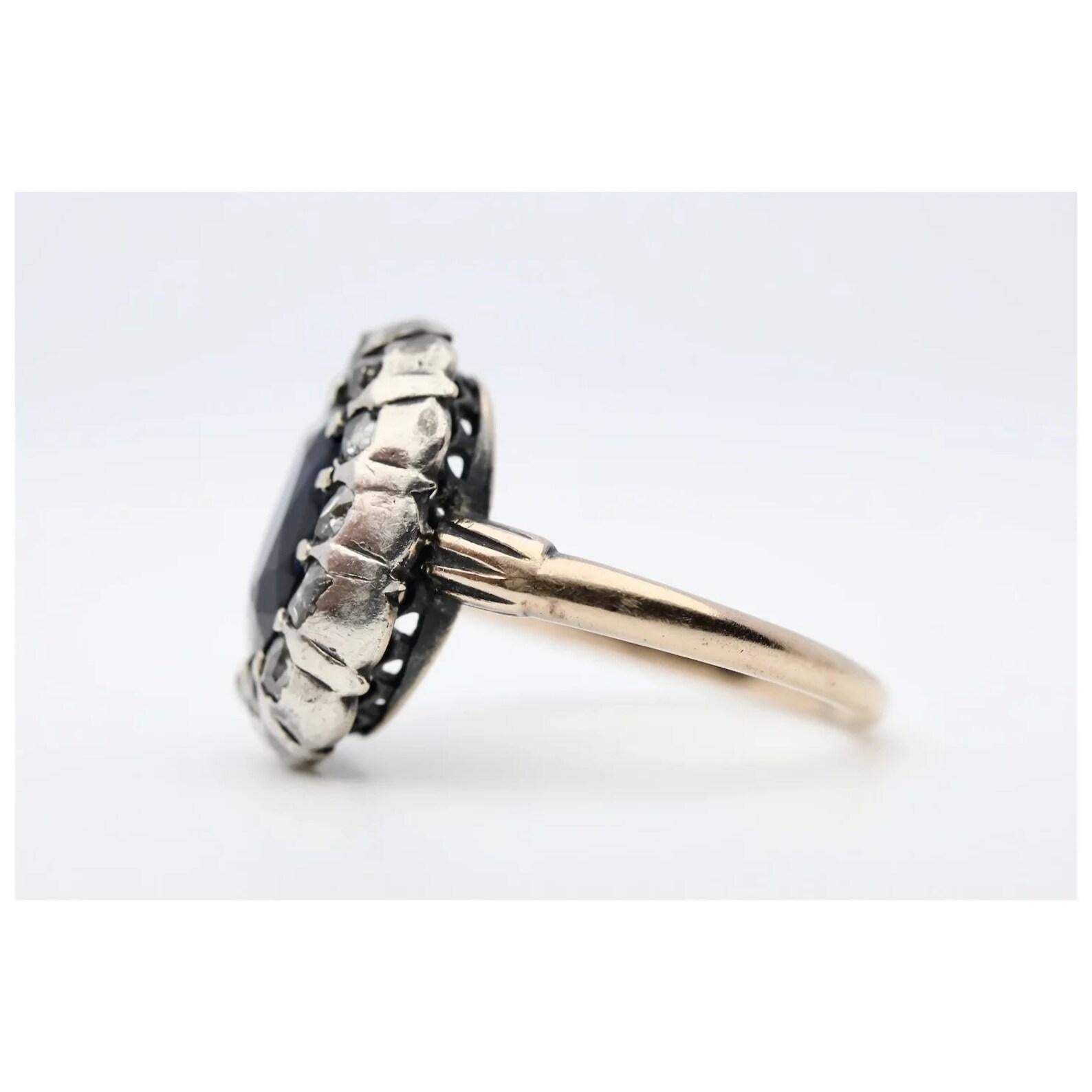 An original early 19th century Georgian period sapphire, and rose cut diamond halo style ring in silver and rose gold. Centered by a 2.50 carat natural vivid blue sapphire of beautiful VS clarity. Encircling the sapphire are a dozen sparkling rose