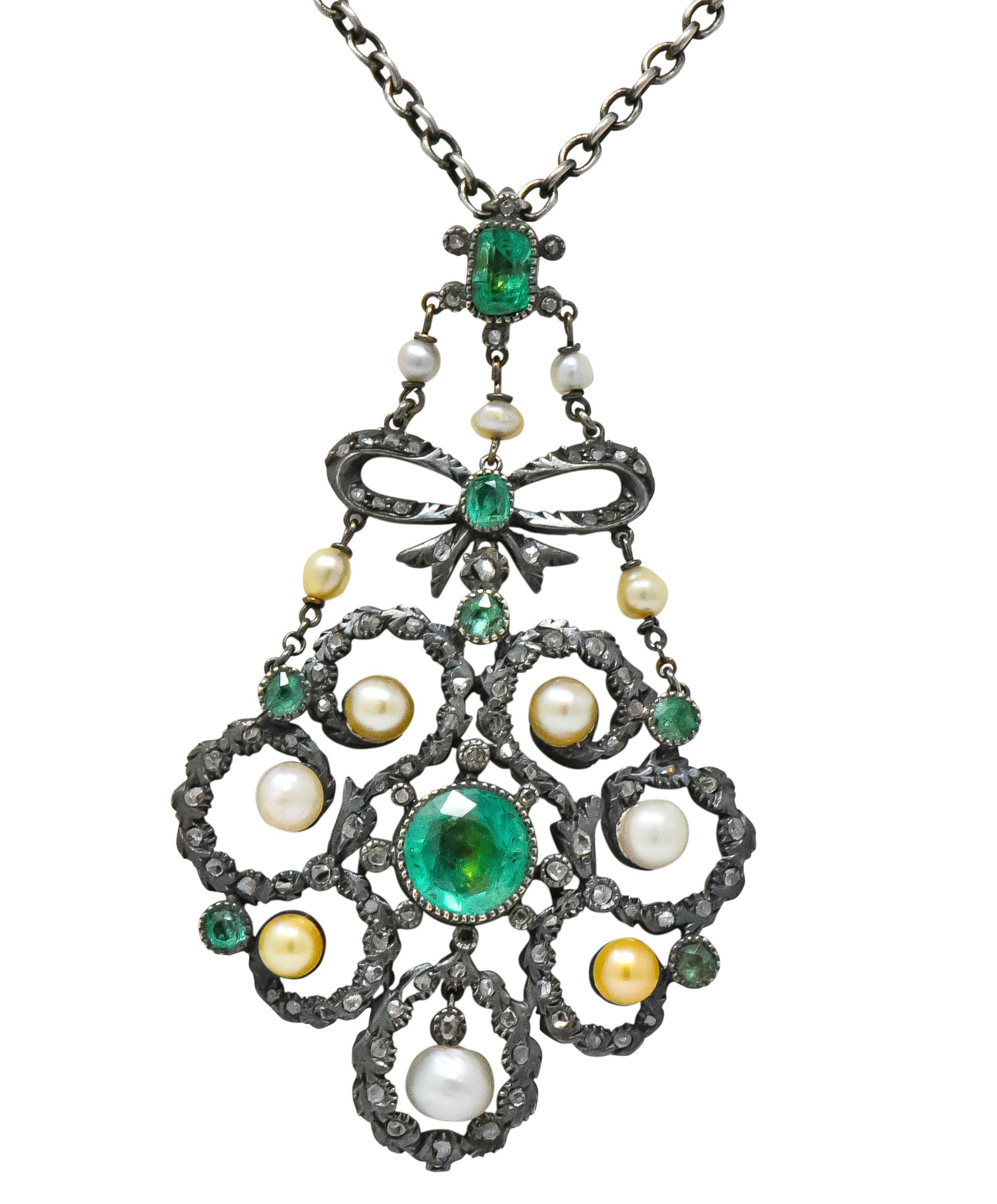 Silver pendant designed with bow and scrolling garland motif set throughout with rose cut diamonds and freshwater natural pearls, varying in color with warm overtones

With bezel set foil backed emeralds weighing approximately 3.50 carats total,